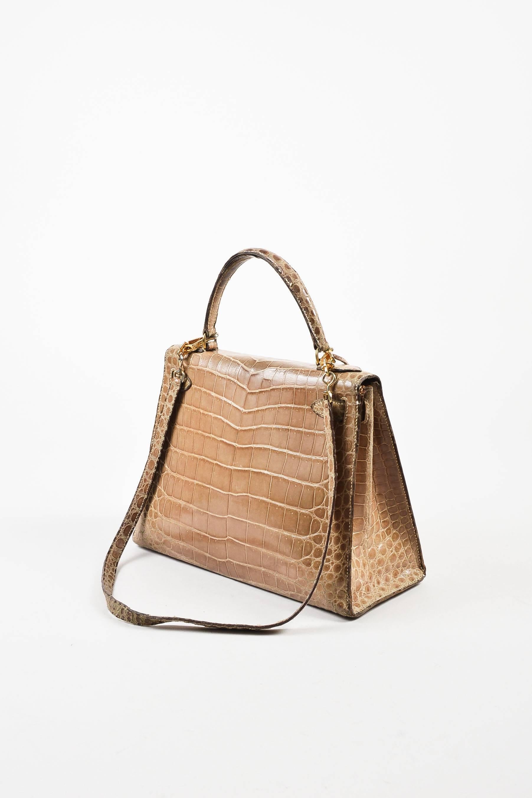 Comes in box with dust bag. Circa 1982, this vintage 28cm Kelly bag is made from taupe colored crocodile leather and accented with gold-tone hardware. It has one flat top strap and a removable shoulder strap. Front straps and turn lock can be