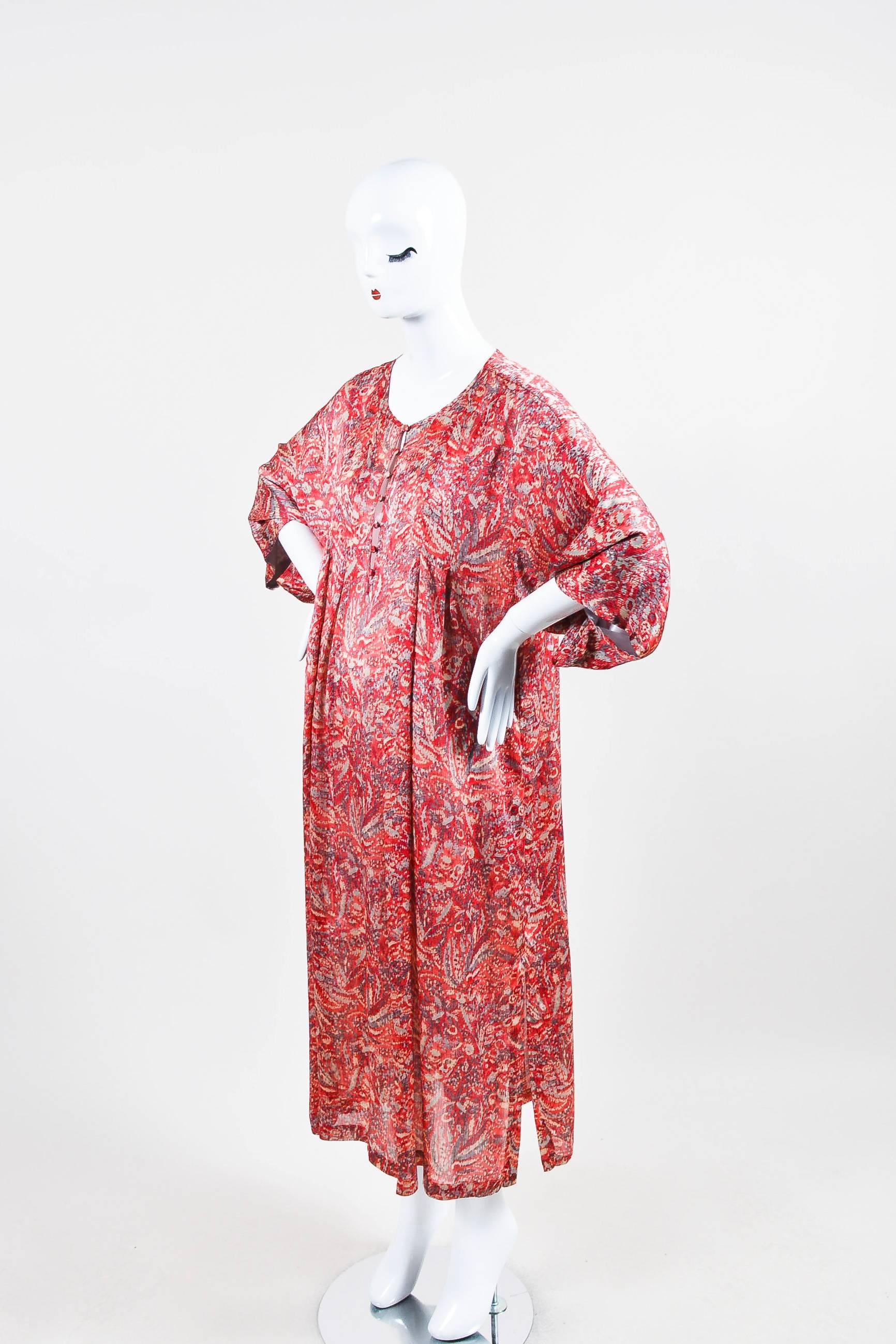 Constructed of luxe satin, this oversize muumuu-style dress is perfect for lounging with its wide sleeves, buttoned partial front placket, scoop neck, inverted pleats radiating from the bust and yoke, and relaxed fit. All-over multicolored print.