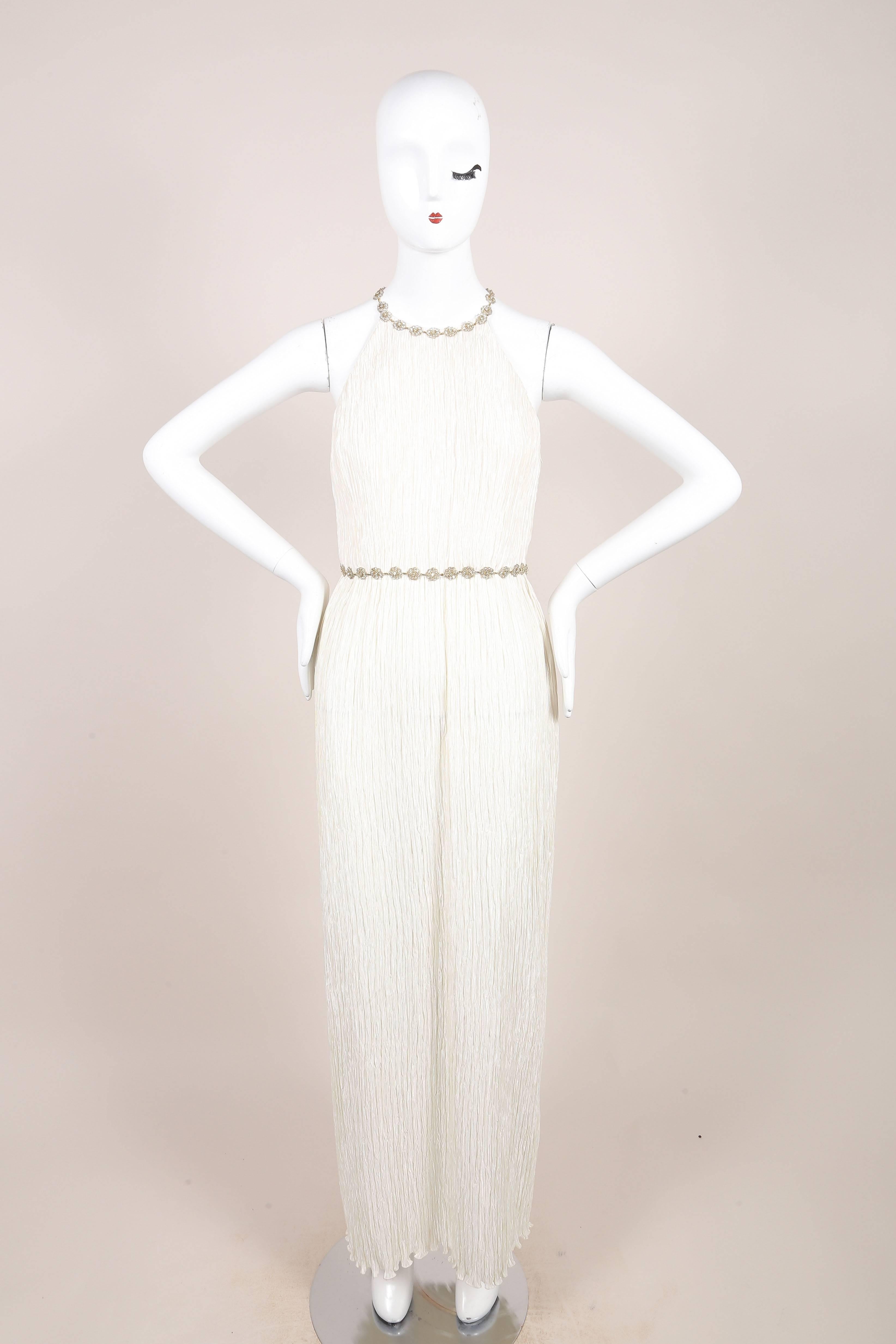 This sleeveless embellished gown comes with a matching shawl. Crinkled ivory fabric. High, rounded neckline. Floor length hemline. Metallic gold and silver, sequin embellished/beaded straps at shoulders at upper back.
Metallic gold and silver,