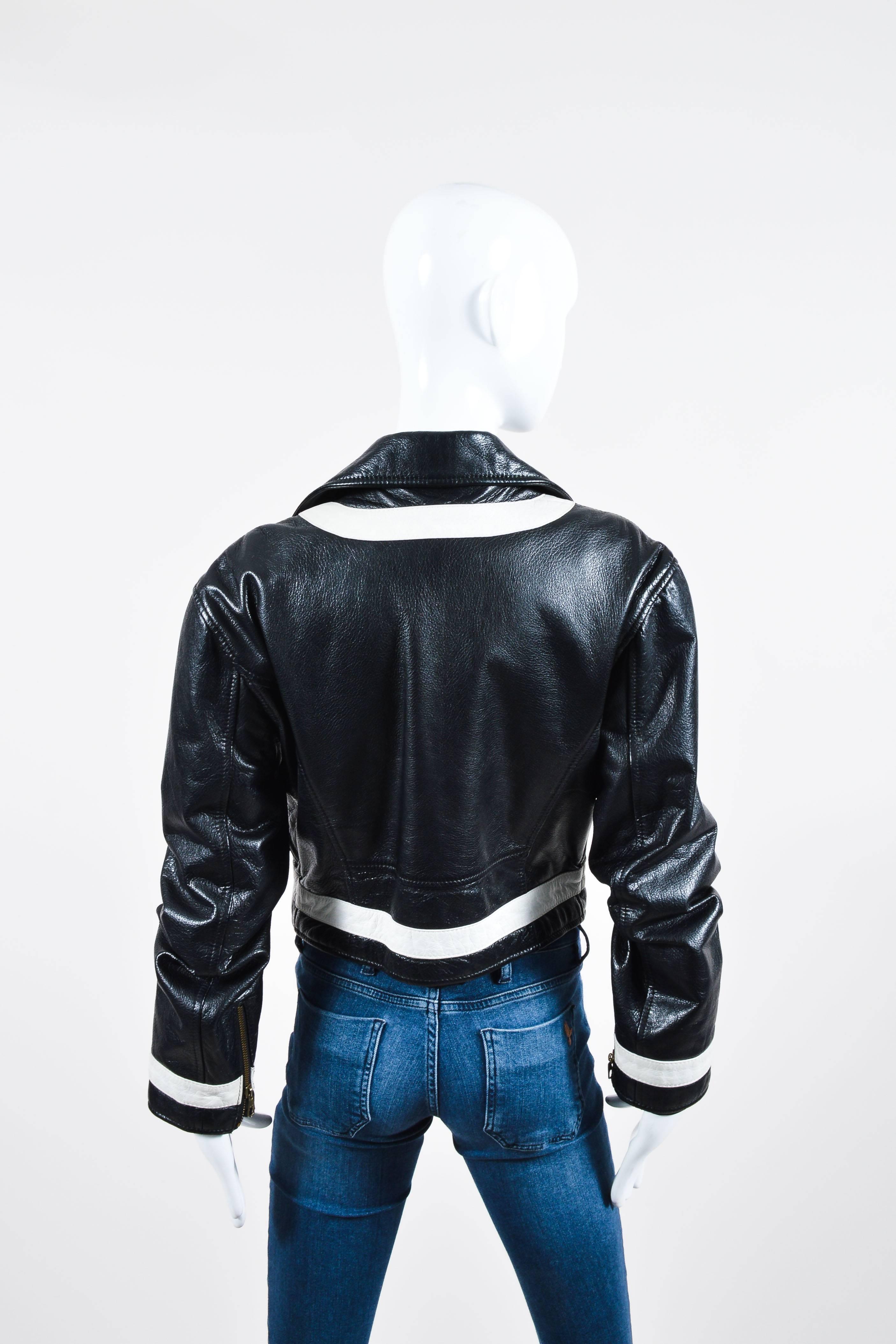 Black leather moto jacket. Cropped length. White leather stripes. Long sleeves with zippers. Gold-tone faux buttons with hearts read, "CHEAP & CHIC." Zip and flap pockets. Off-center front zip closure. Lined.

Additional