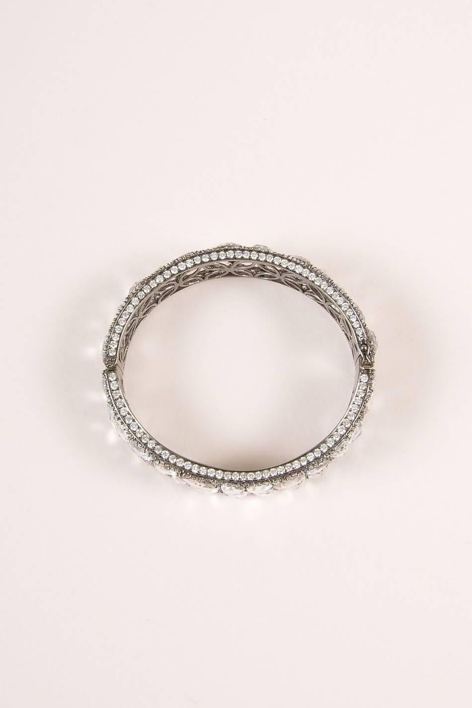 Gorgeous multi-faceted, chunky white sapphire gemstone-encrusted bracelet. Pave diamond border and scattered throughout gemstones are set in 18 karat white gold frame. Hinged opening with box clasp closure and two safety mini prong clasps.Interior