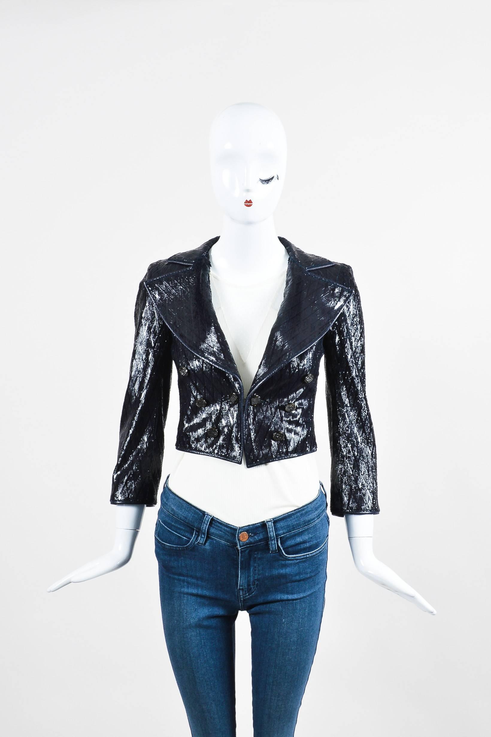 Unique jacket to make a bold statement to an outfit. Intricate feathered laser cut detail on leather with a glossy patent finish. Wide peak lapels. 3/4 sleeves. Hits at waist. Padded shoulders. Front double-breasted embellished button closure.