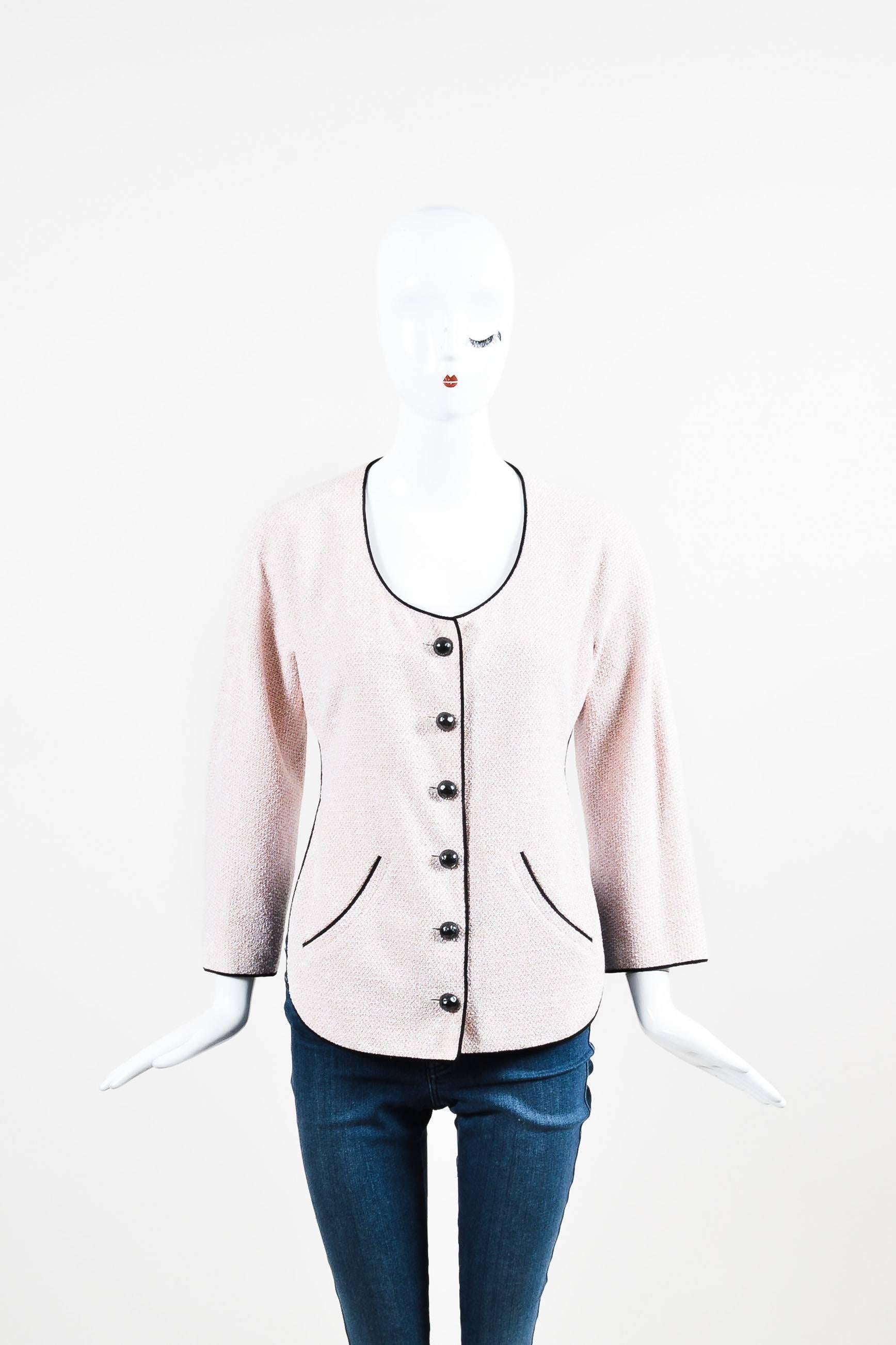 Feminine and unique jacket by Chanel. Light pink tweed with solid black, satin trims. This fun design features an open back with a tie across. Button front closure with 