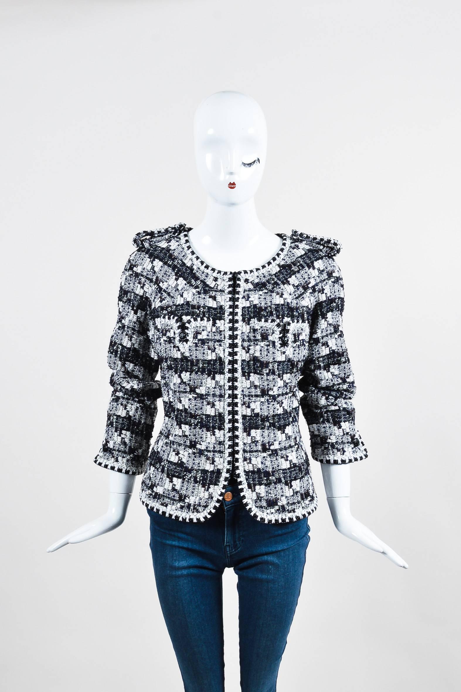 Black and white woven tweed jacket with touches of navy, brown, and metallic silver. Three quarter length sleeves. Collarless. Black bead trim. Decorative epaulets. Buttoned chest pockets. Black 'CC' logo buttons. Zips up front. Lined.

Additional