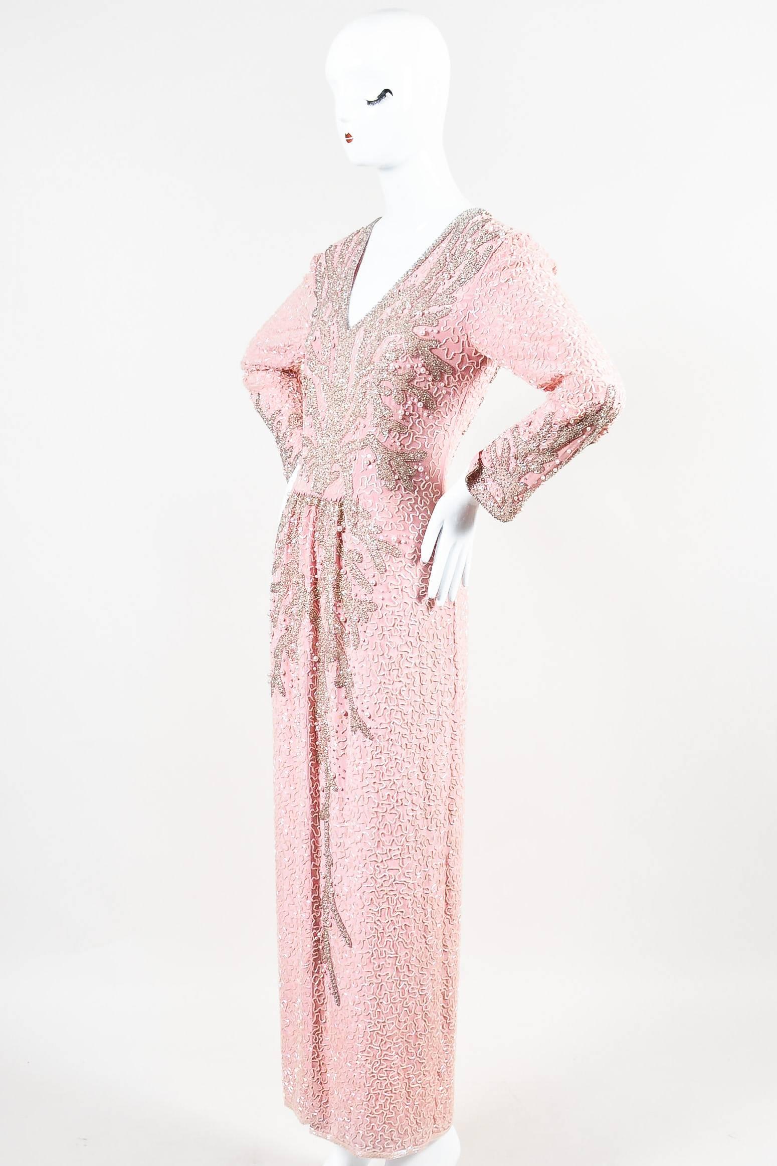 Fun and eye-catching vintage dress by Oleg Cassini. Pink color with silver-tone beading throughout in a coral-like pattern. Faux pearl embellishments and sequins. V neckline and a slit at the front hem. Vented cuffs. Back zipper closure. Hits
