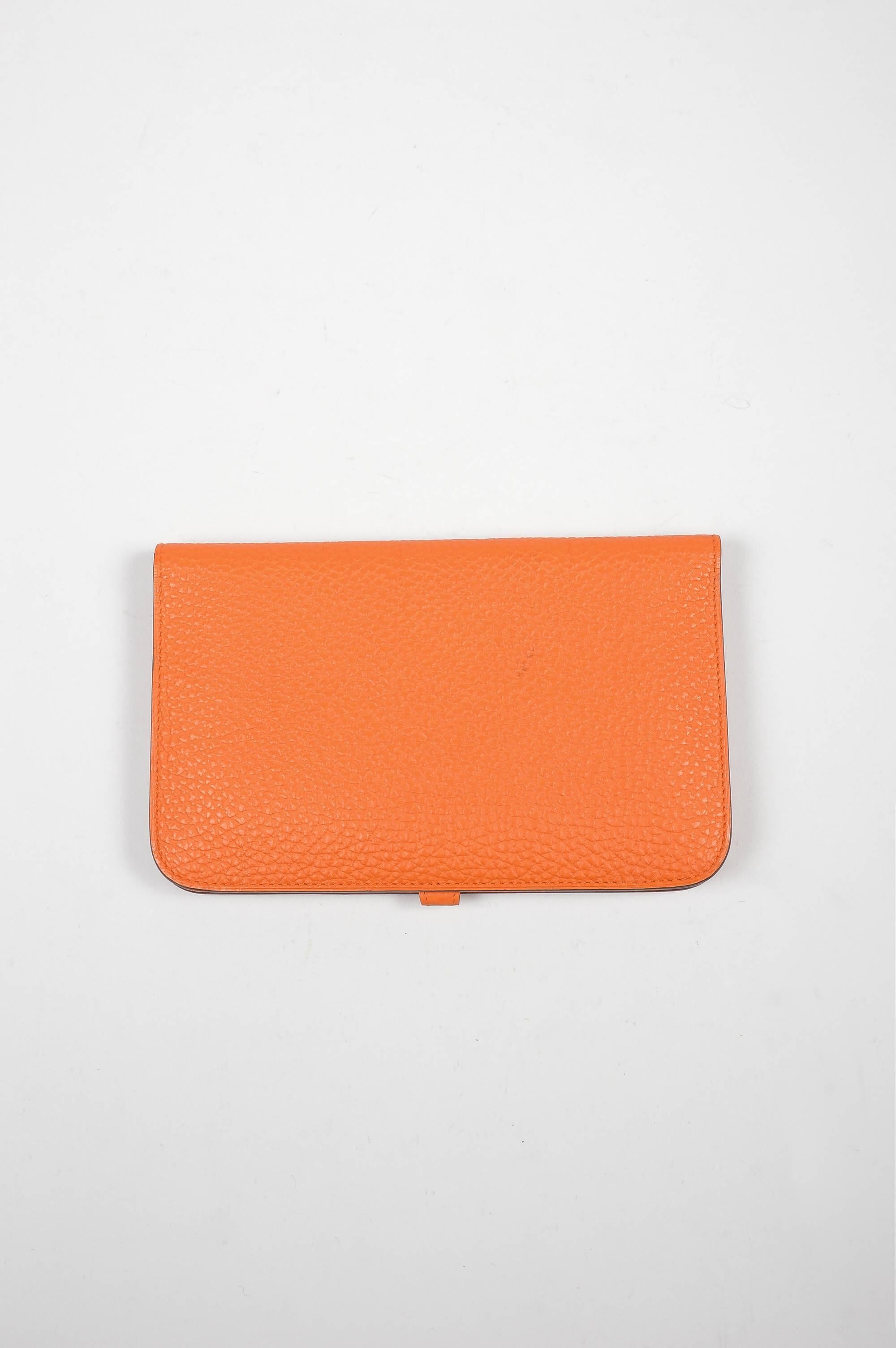 Elegant Hermes Togo leather Dogon wallet in a "capucine orange" color. A statement piece that will have heads turning when you are on your next shopping trip. Palladium "Clou de Selle" tab and leather strap closure. Grained