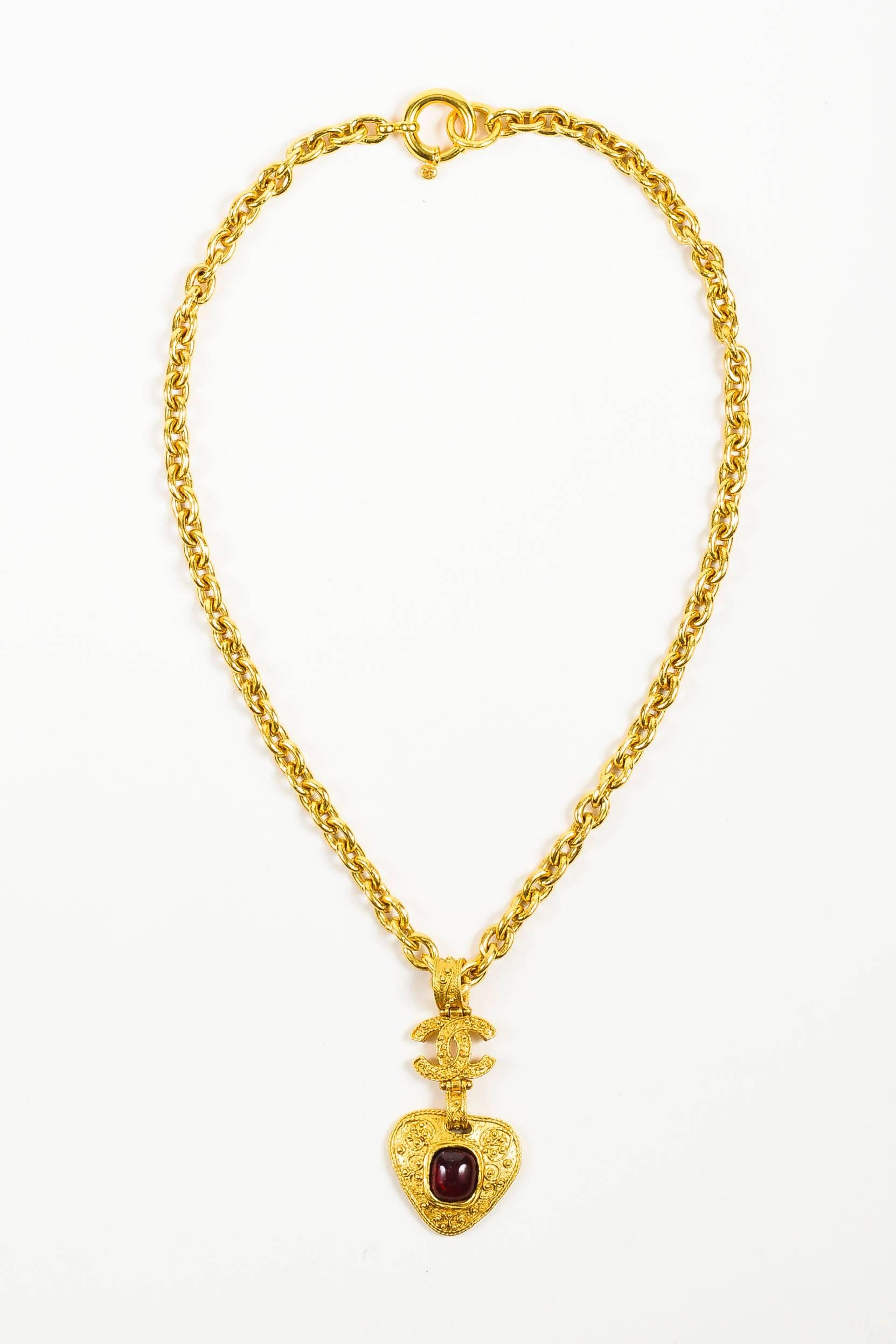 Ornate, vintage Chanel necklace from the 1994 Fall Collection. This stunning piece adds instant upscale glamour to any ensemble. Gold tone metal. Long, rolo chain. Textured drop pendant featuring the iconic 'CC' logo and a glossy, red Gripoix glass
