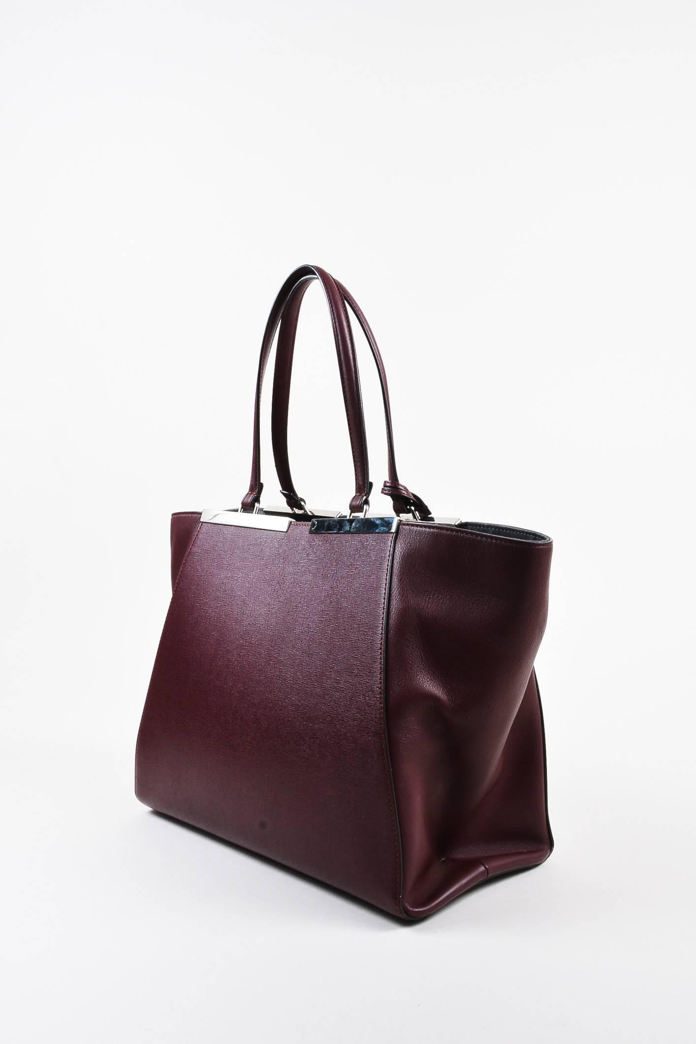 Retails at $2550. Sleek tote to carry your everyday work essentials in luxury. Trapeze shape. Handcrafted in Italy. Supple, buttery calf leather construction; textured detail on front and back. Silver-tone hardware. Top flat handles connected to