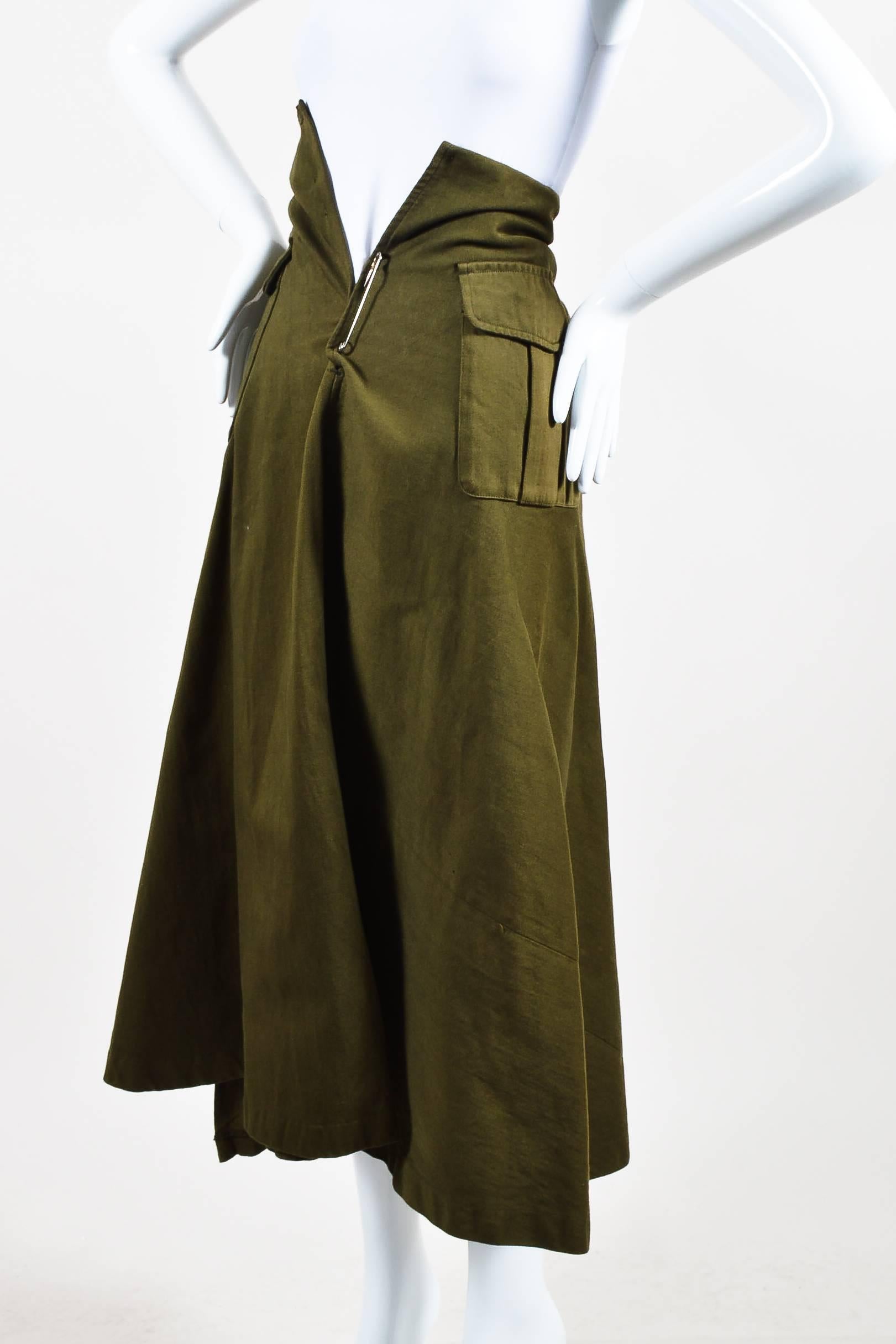 Vintage a-line skirt. Constructed of cotton. Army green. Flap pockets. Large safety pin fastening in front. Lined.