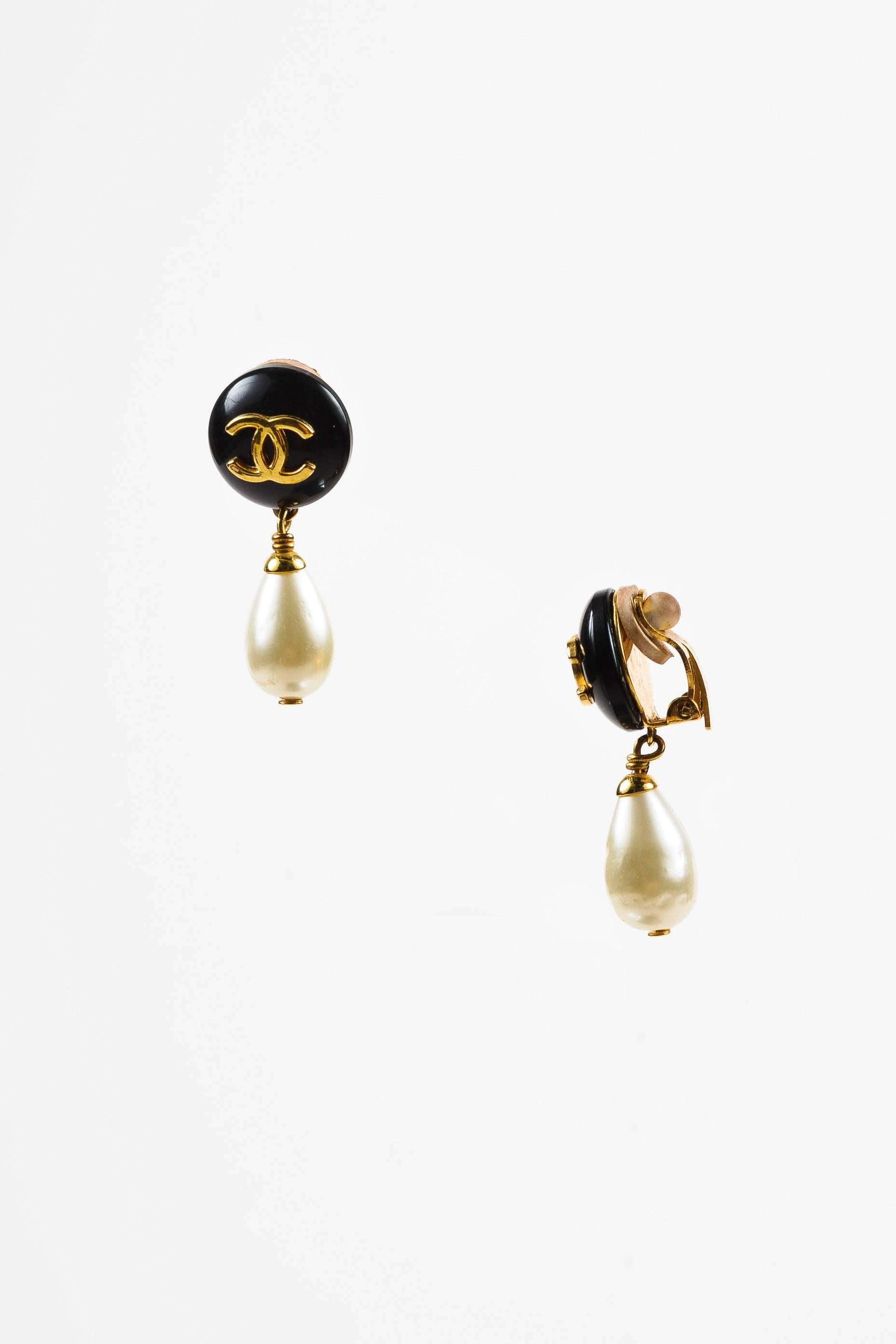 Vintage earrings from the Spring 1996 collection, features an elegant drop silhouette, an interlocking 'CC' accent on resin, and a dangling faux pearl detail. Clip-on back. Comes in a box. A subtle piece of iconography, these earrings are a