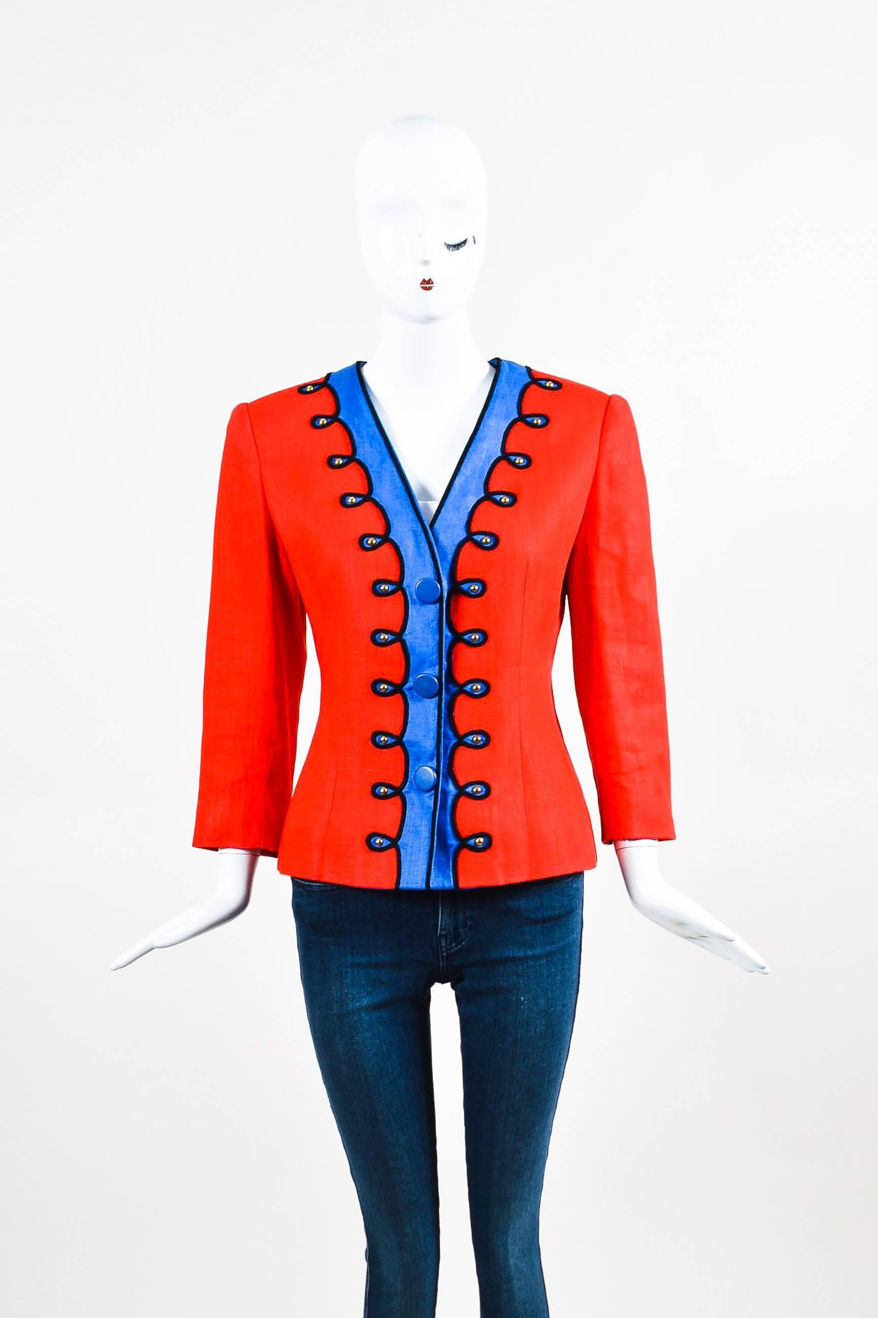 Bright and fun jacket by Givenchy Nouvelle Boutique. This vintage piece has a marching band feel with vibrant hues of red and blue and gold-tone studs. Black embroidered detailing. Large, padded shoulders. Snap front closure with a V neckline.