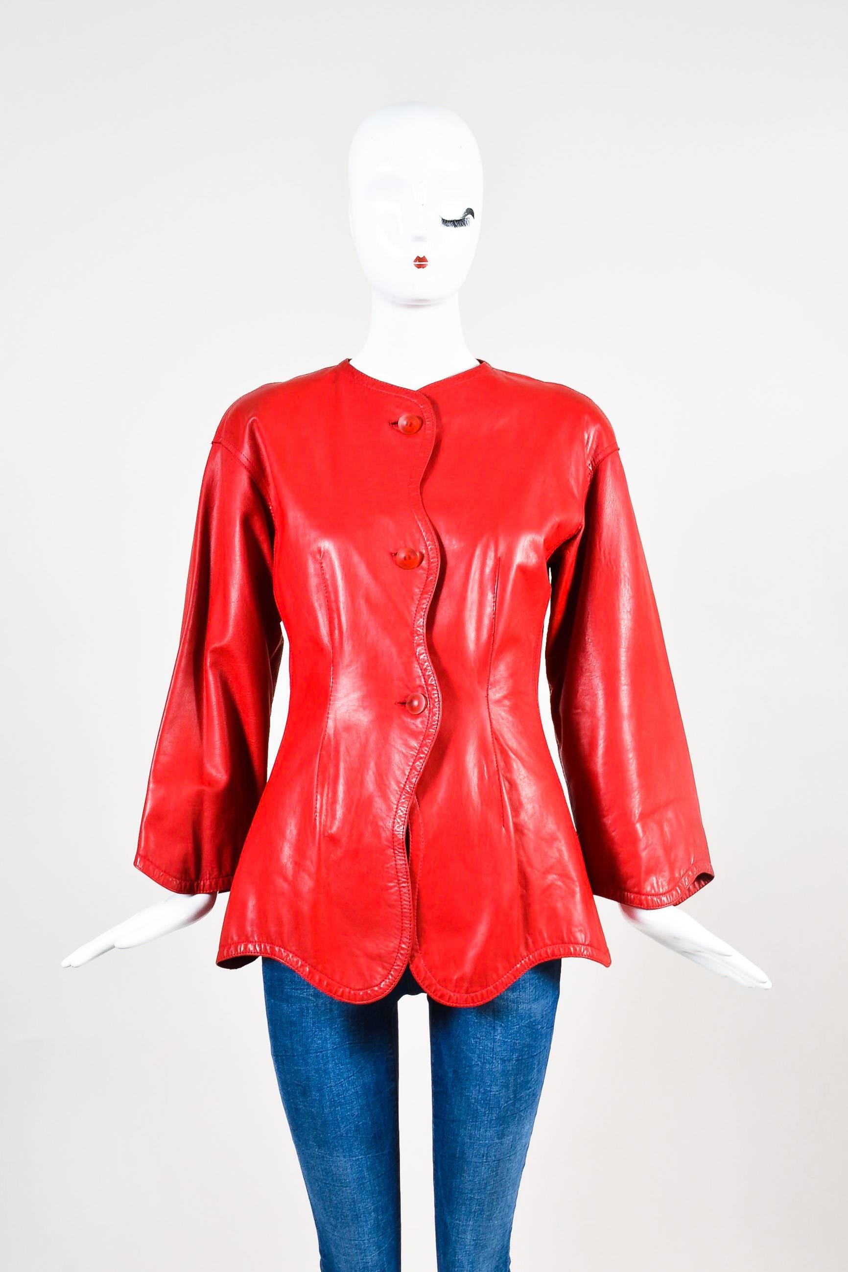 This classic leather jacket makes a bold statement. Supple leather construction. Translucent red buttons. Scalloped hem, sleeves and front opening. Jewel neckline. Slight drop shoulder. Long sleeves. Hits at hips. Padded shoulders. Front button