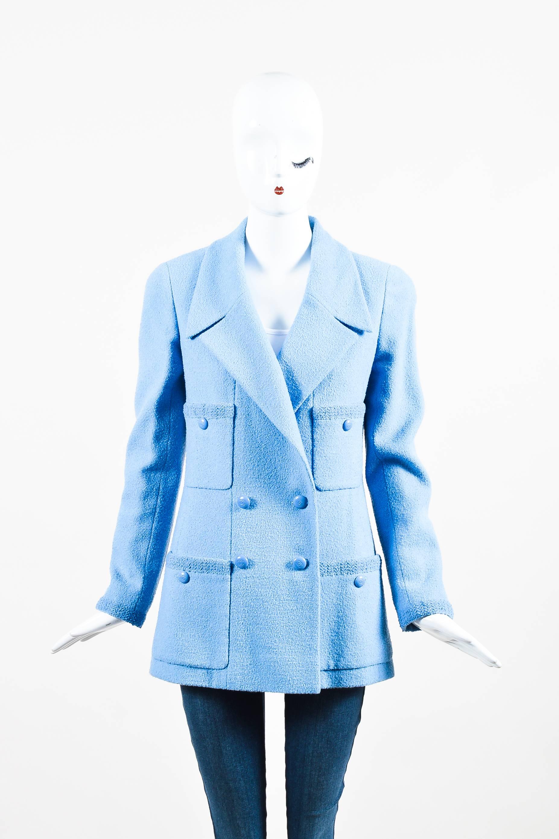 Baby blue wool double breasted long sleeve jacket from Chanel Boutique. Four flat lay pockets on the front of jacket have 'CC' logo engraved large round blue buttons for closure. These buttons also appear down the front of jacket and at the bottom