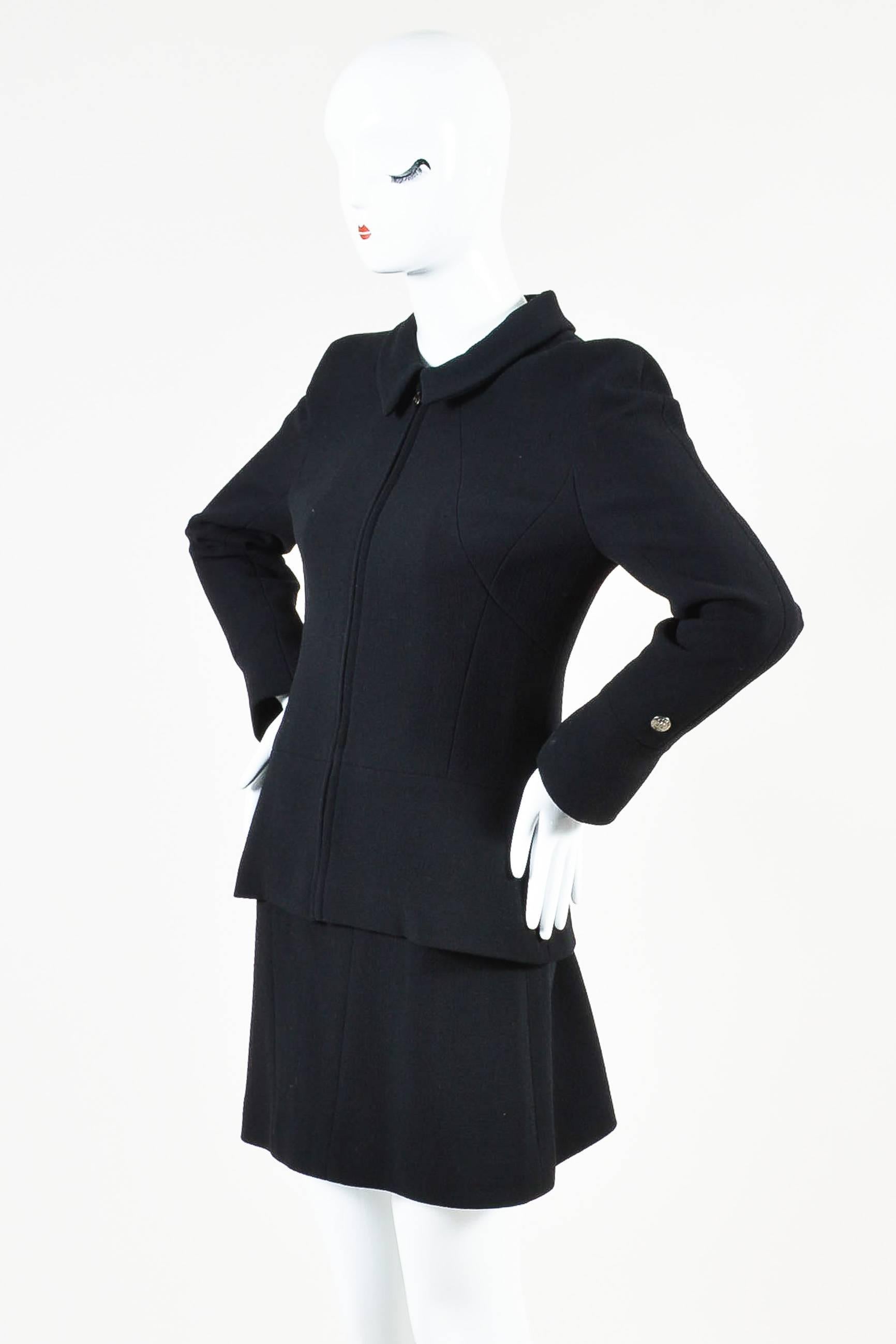 Classic black suit that exudes timeless style. From the fall 1997 collection. Wool construction. Textured boucle weaving throughout. Jacket: Flat collar. Long sleeves; flared at bottom. Slightly flared hem. Hits at hips. Paneled seams. Front zip