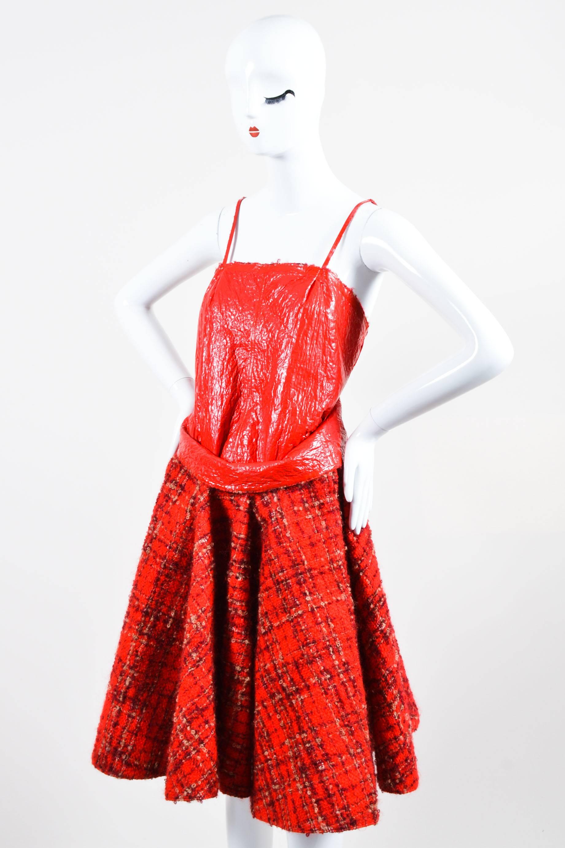Retails at $1685. Stand out from the rest in this uniquely constructed dress. Tweed wool with checkered pattern throughout. Contrast slick polyurethane detail on body and underneath skirt. Draped skirt; partially exposed at sides. Sleeveless with
