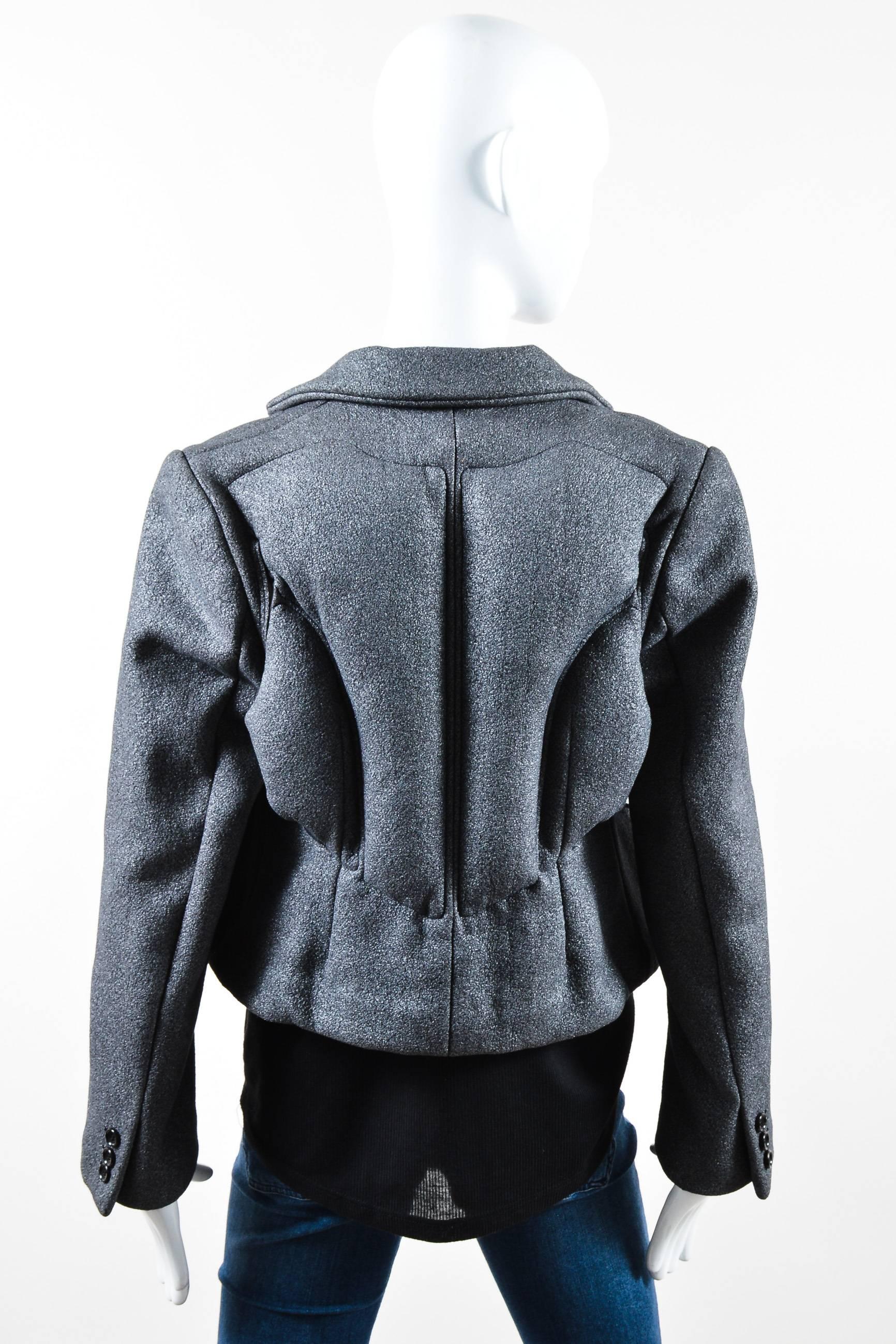 Gray jacket with metallic glitter. Long sleeves. Notch collar. Lightly padded with heavy padding on back. Cut out slits at sides and on back with zip pockets on interior. Buttons at ends of sleeves. Buttons up front. Lined.

Additional