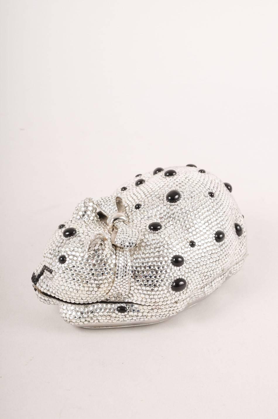 Comes in Judith Leiber dustbag! Sleeping cat minaudiere has bow detail collar and metallic leather underside. Push lock style closure at side. Silver rhinestone embellishment throughout exterior. Small black dot details. Interior metal tag reads