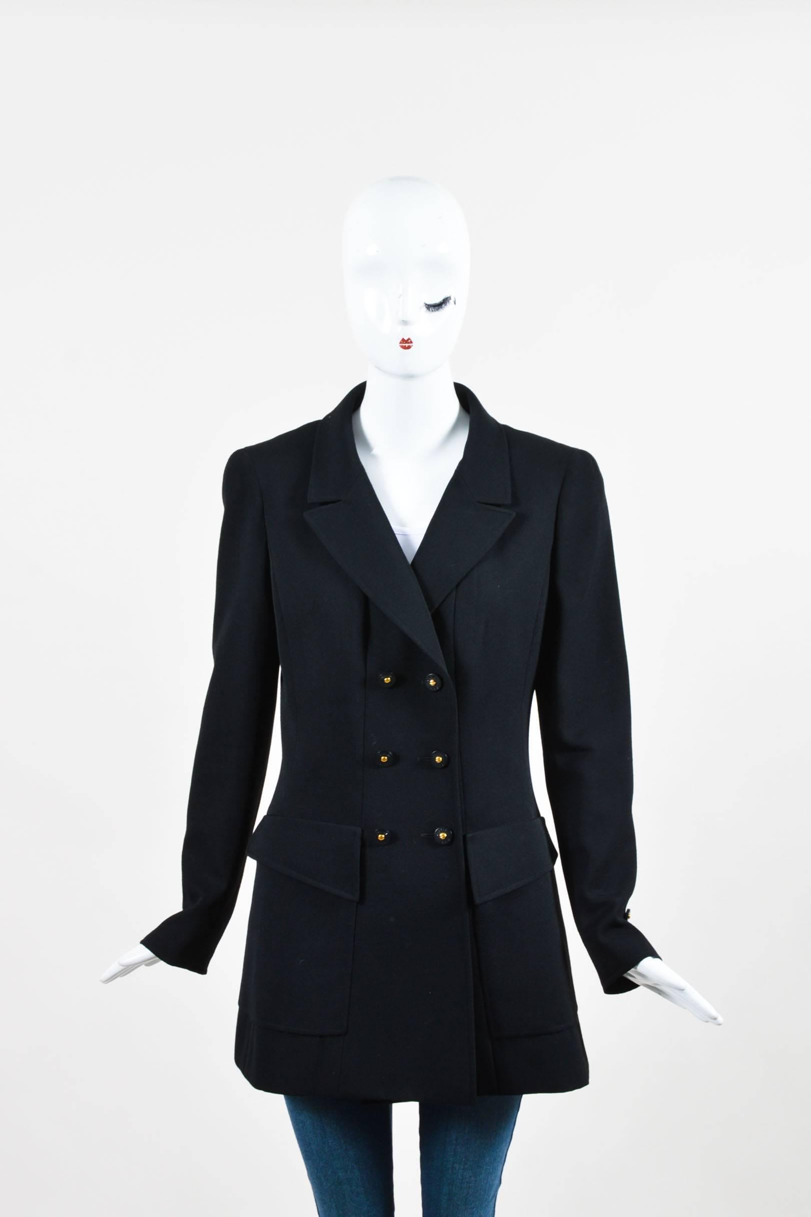 Black blazer from the 1997 Spring Collection. Constructed of wool. Notch collar. Padded shoulders. Long sleeves with button cuffs. Two large front patch pockets. Front double breasted button closure. Black and gold-tone buttons read 