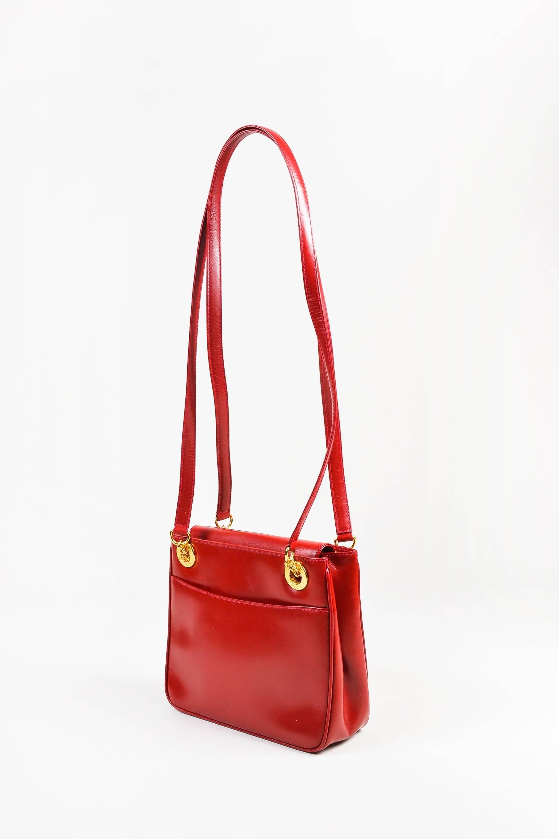 Vintage Gucci red dual strap shoulder bag constructed of box calf leather. Features gold-tone metal hardware throughout exterior and open top pockets at front and back exterior walls. Magnetic snap flap closure. Lined. with leather. Serial: 001 46