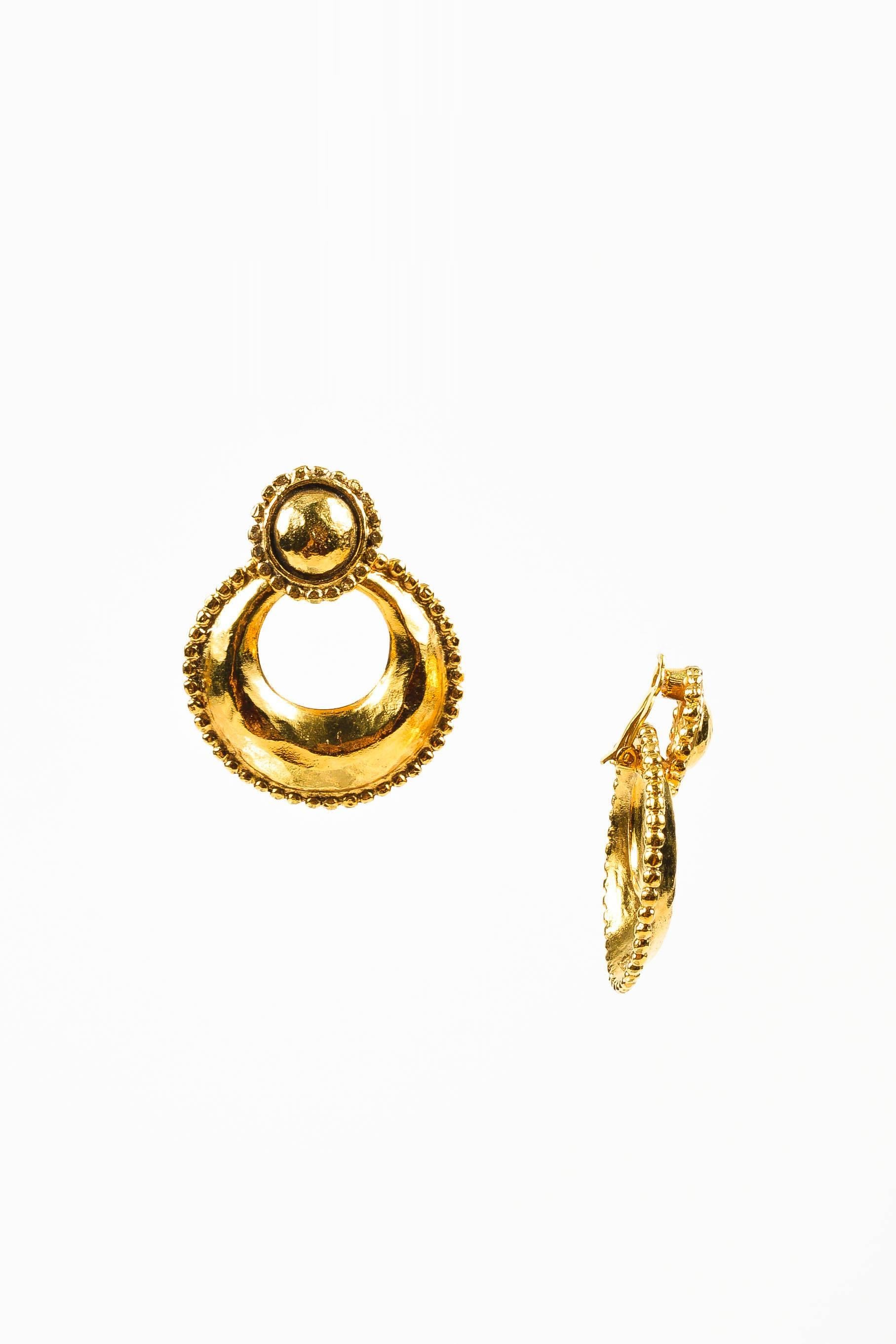 Vintage Chanel earrings from Collection 25, circa 1988. These baroque earrings are two styles in one. Circular buttons hold a dangling hoop that may be removed for a more understated look. Hammered gold tone metal with caviar textured border. Clip