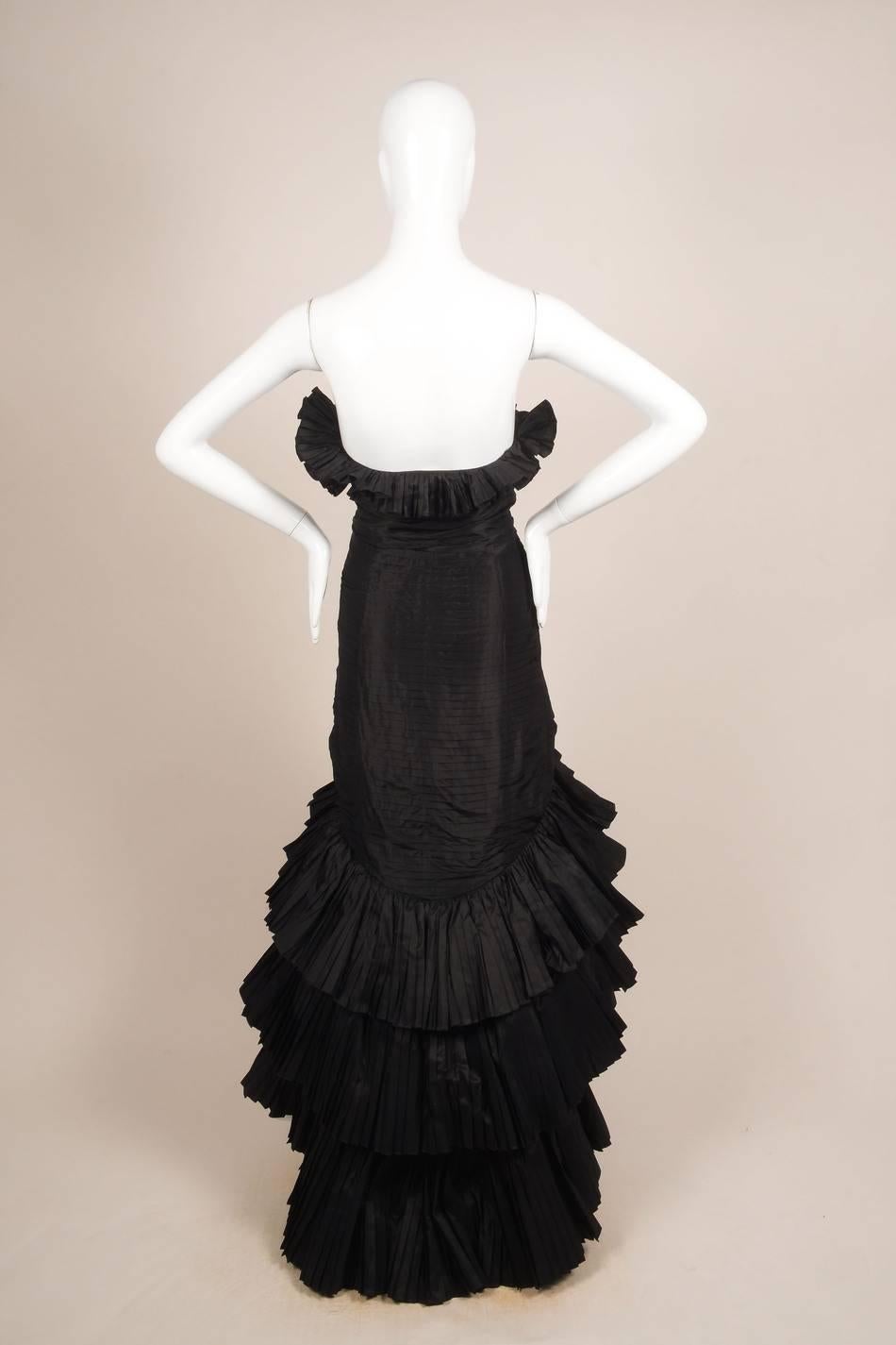 Strapless. Full-length. Accordion pleating detail throughout. Ruffle pleated trim around bust. Layred tiered pleating down skirt. Tulle inserts in between skirt layers. Hidden side zip closure with hook-and-eye closure. Lined. 

Size: Unknown