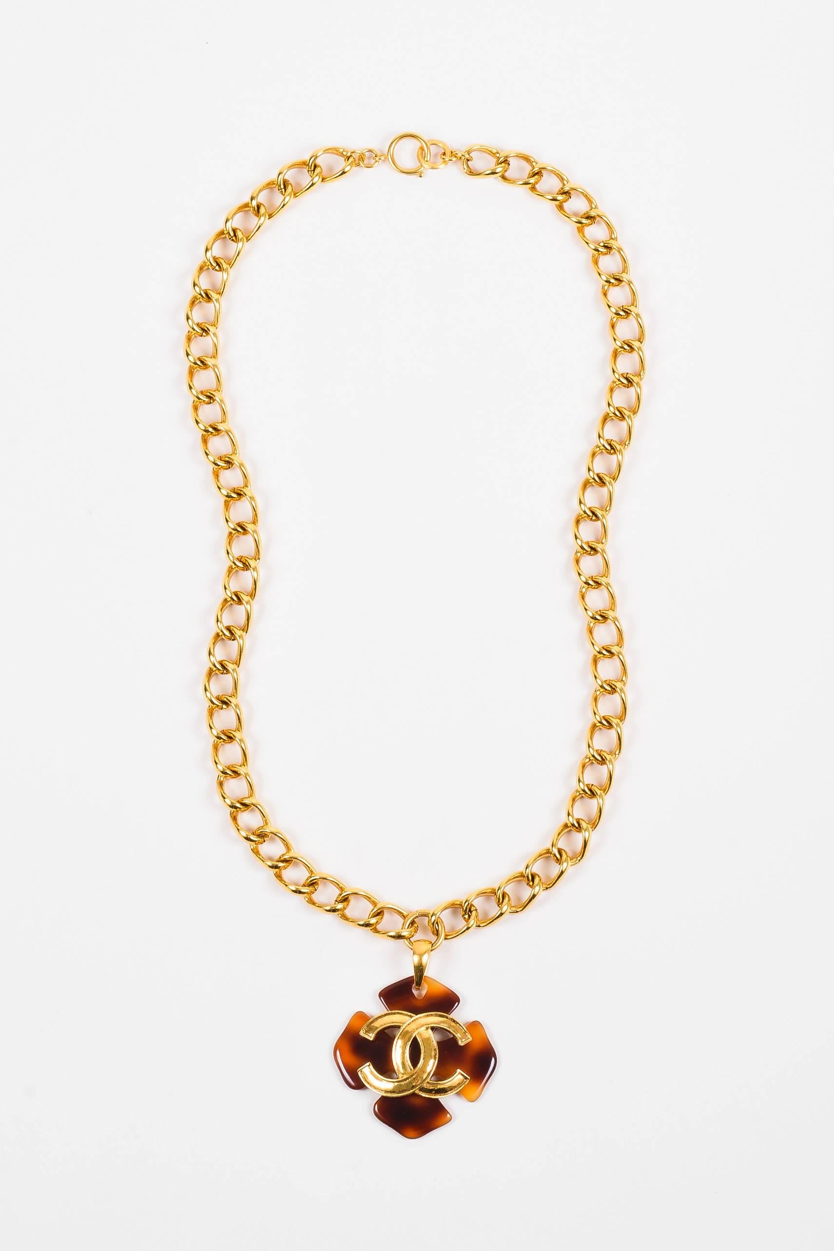 From the 1995 Spring collection this vintage Chanel necklace features a tortoise shell clover shaped pendant with a gold-tone 'CC' logo on the front. Large gold-tone chain secures with spring ring in back. The perfect statement Chanel piece to add