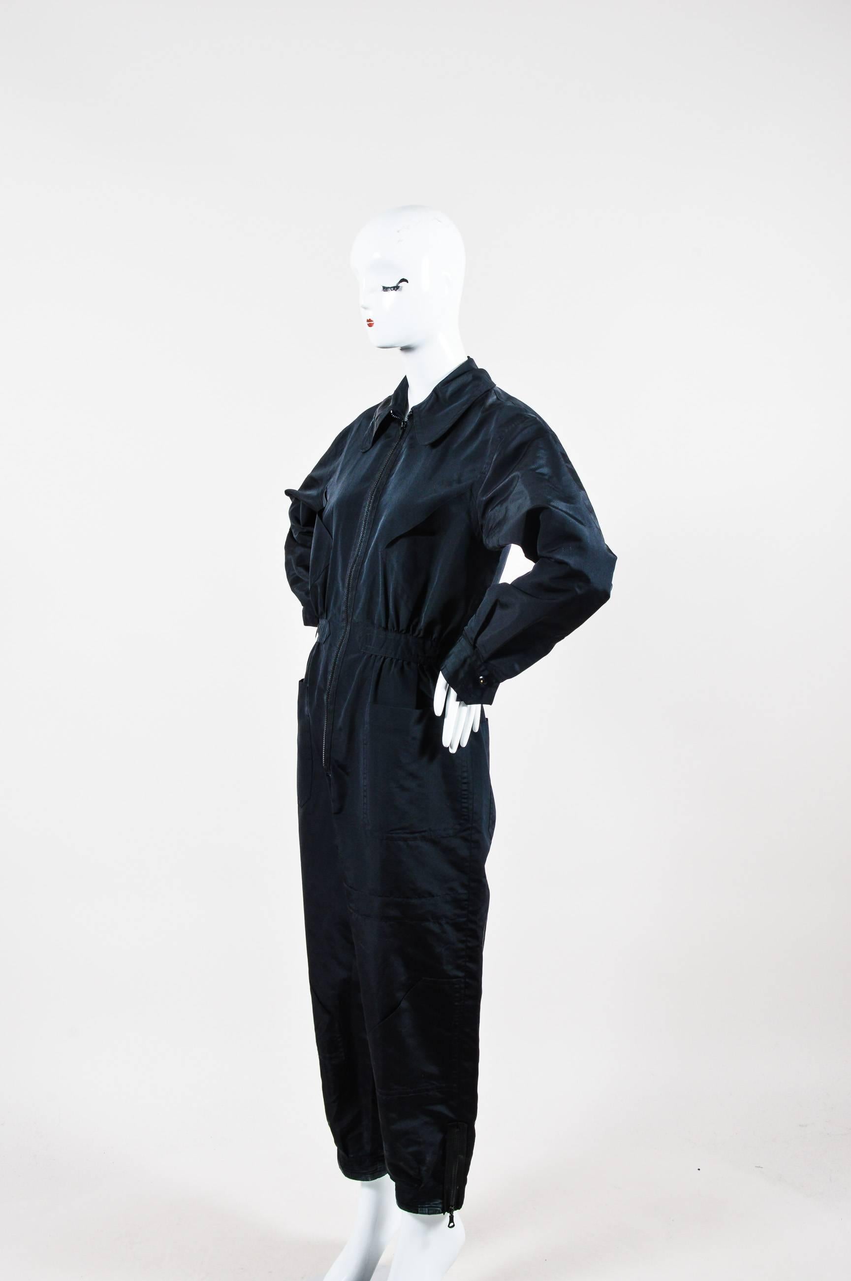 Industrial looking Chanel silk jumpsuit with exposed zippers. Channel your inner pilot in this athletic-look piece. Pair with high heels and a clutch to contrast the silhouette. Large patch pockets throughout. Zippered cuffs and ankles. Tapered in
