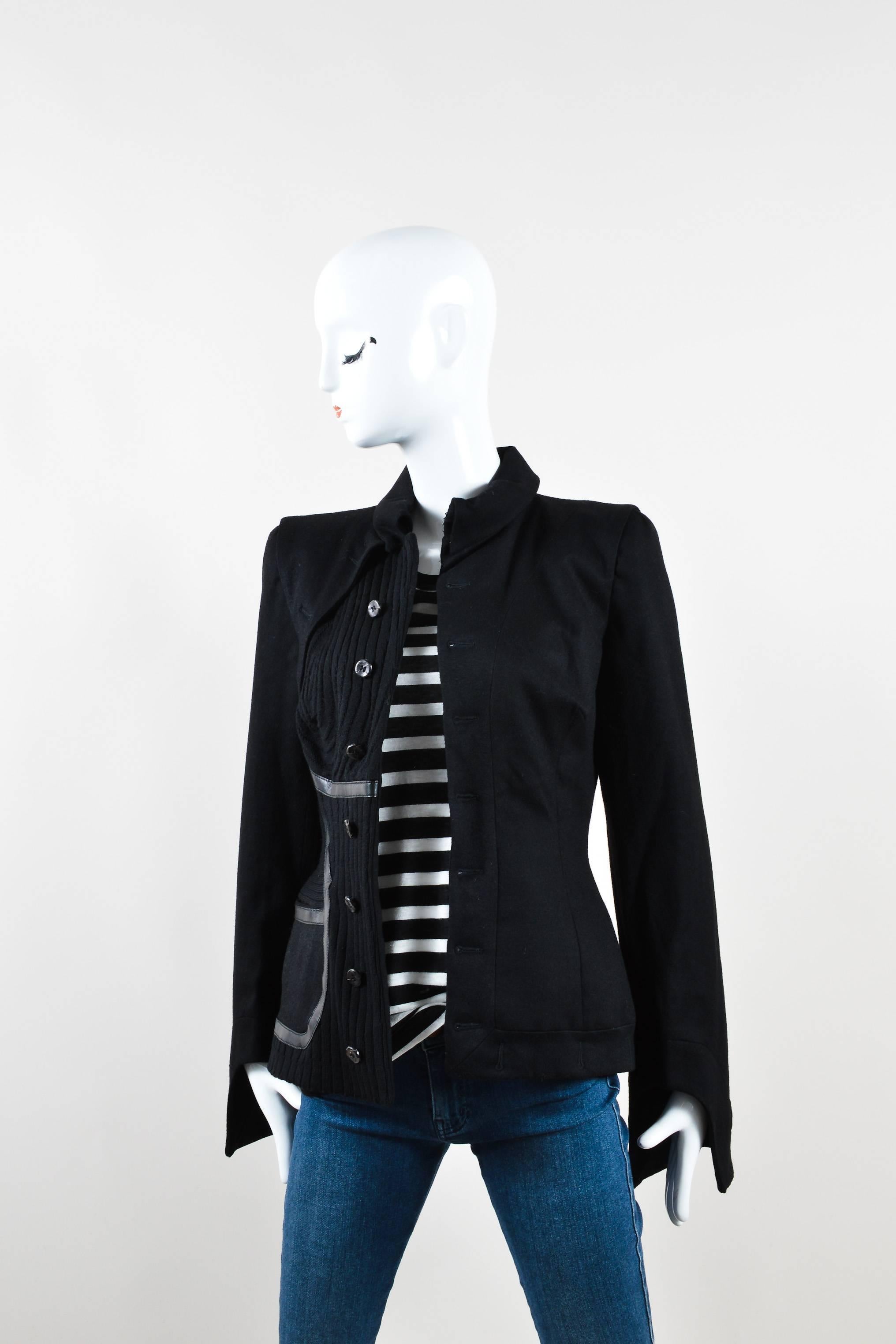 Unique jacket for cooler weather. Ribbed detail on right side. Leather trim. Spread collar. Hits at hips. Panel detail on right shoulder. Cut out detail at bottom of sleeves. Padded shoulders. Front hook-and-eye closure underneath collar. Front