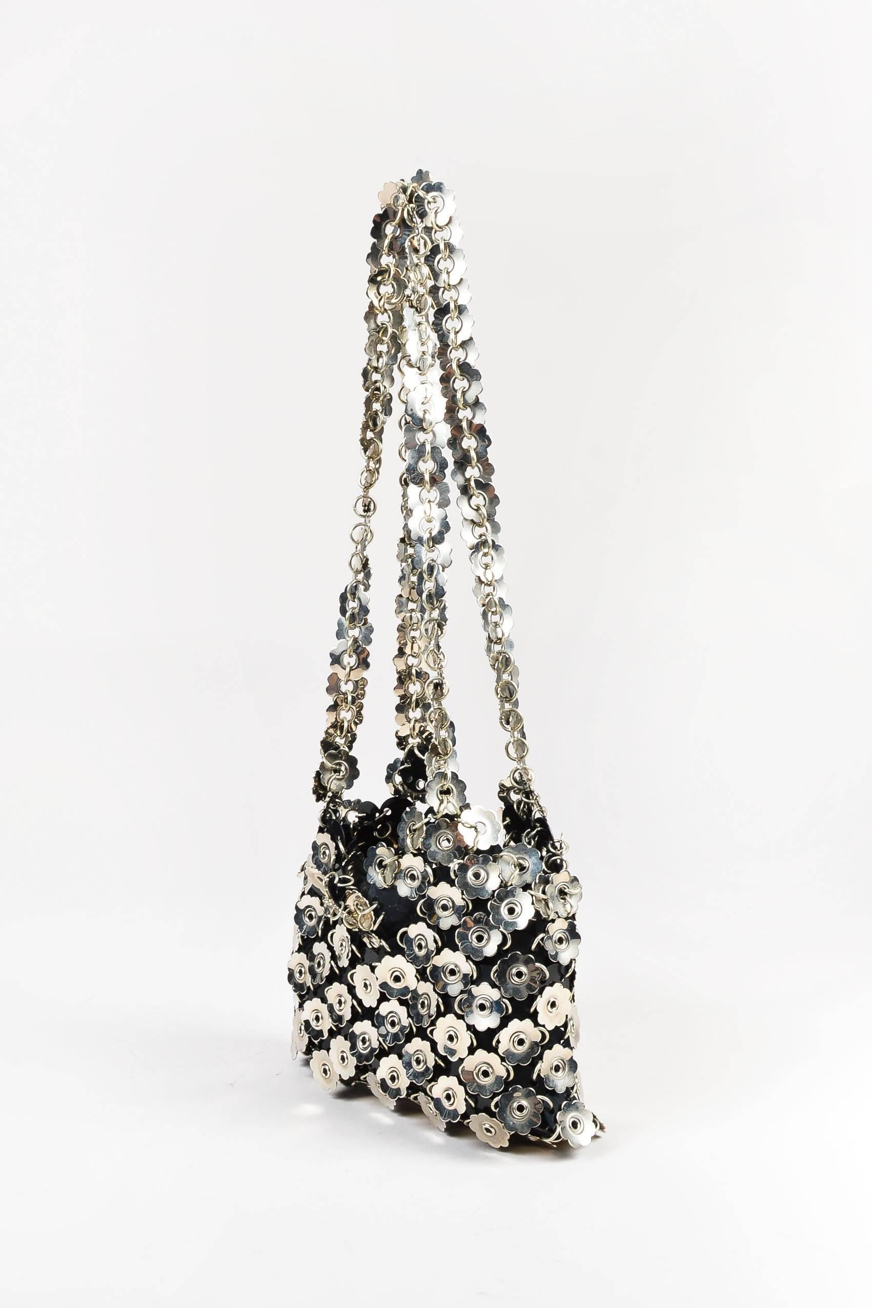 Vintage shoulder bag from Paco Rabanne features silver-tone flower metal and black circular plastic embellishemtns. Two straps for wear. Top zipper for closure. Lined.

Interior features: Lining

Additional measurements: Strap Length