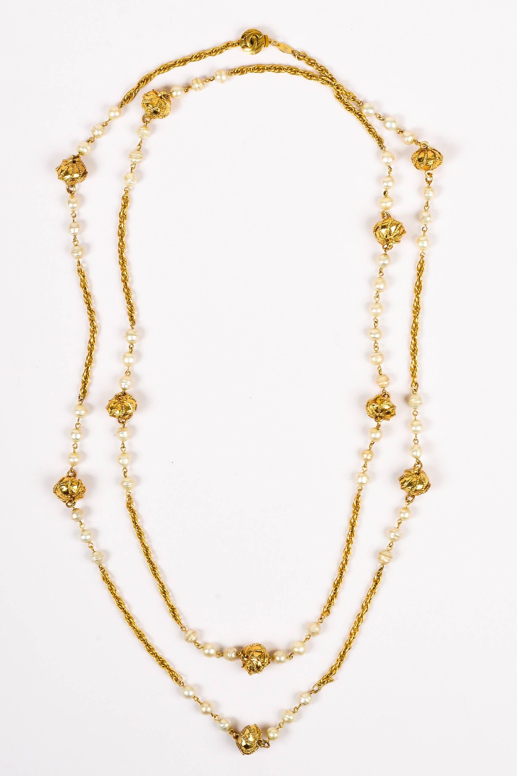 Comes with box. Elegant, vintage Chanel necklace, design circa 1984. This classic collector's item adds a polished finishing touch to any look. Rich, gold-tone metal. Double link chain with rope textured stations & baroque faux pearls. Plunger