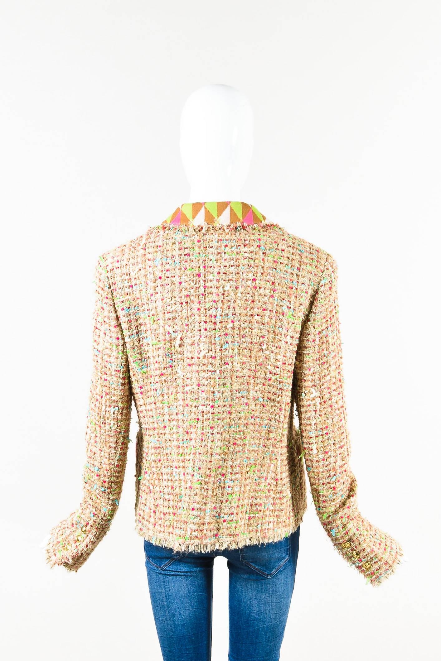 Tan multicolor wool tweed long sleeve collared jacket from Chanel features a frayed trim throughout. Triangle patterned textile on the collar and pockets. Two front open pockets. Flower pin on the lapel. Shoulder pads. No closures.