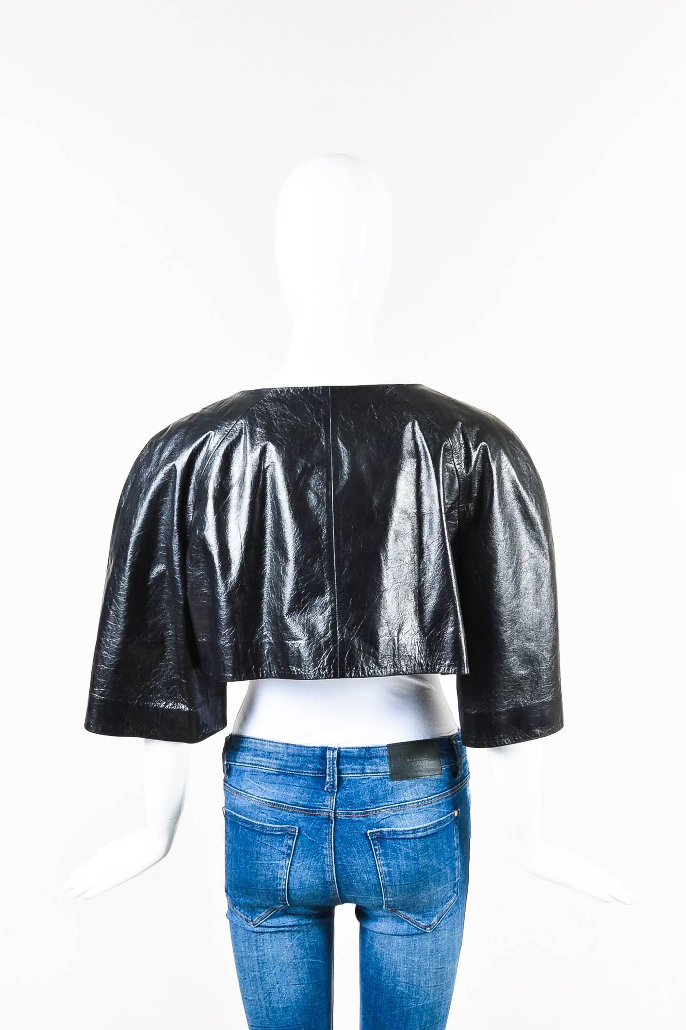 Black leather cropped three quarter sleeve jacket from Chanel. Pearl buttons with 'CC' printed logo down the front for closure. Lined. Comes with a fabric swatch and an extra button.

Condition details: Pre-owned. Heavy wrinkling and minor wear