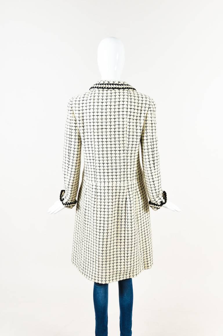 Cream and black checker plaid, long-sleeve, knit coat by Chanel. Features front chest and hand pockets, black button closure, and cuffed sleeves. Cream silk lining.

Additional measurements: Sleeve Length 22.5