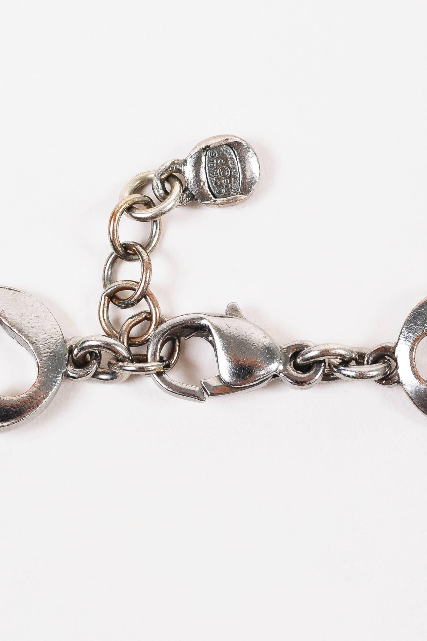 Chic charm bracelet to add the finishing touch to any outfit. Gunmetal-tone metal. Link chain. Circular charms with cut out Chanel symbols. Lobster claw clasp closure. Comes with box.

Measurements: 
Total Length: 7.75