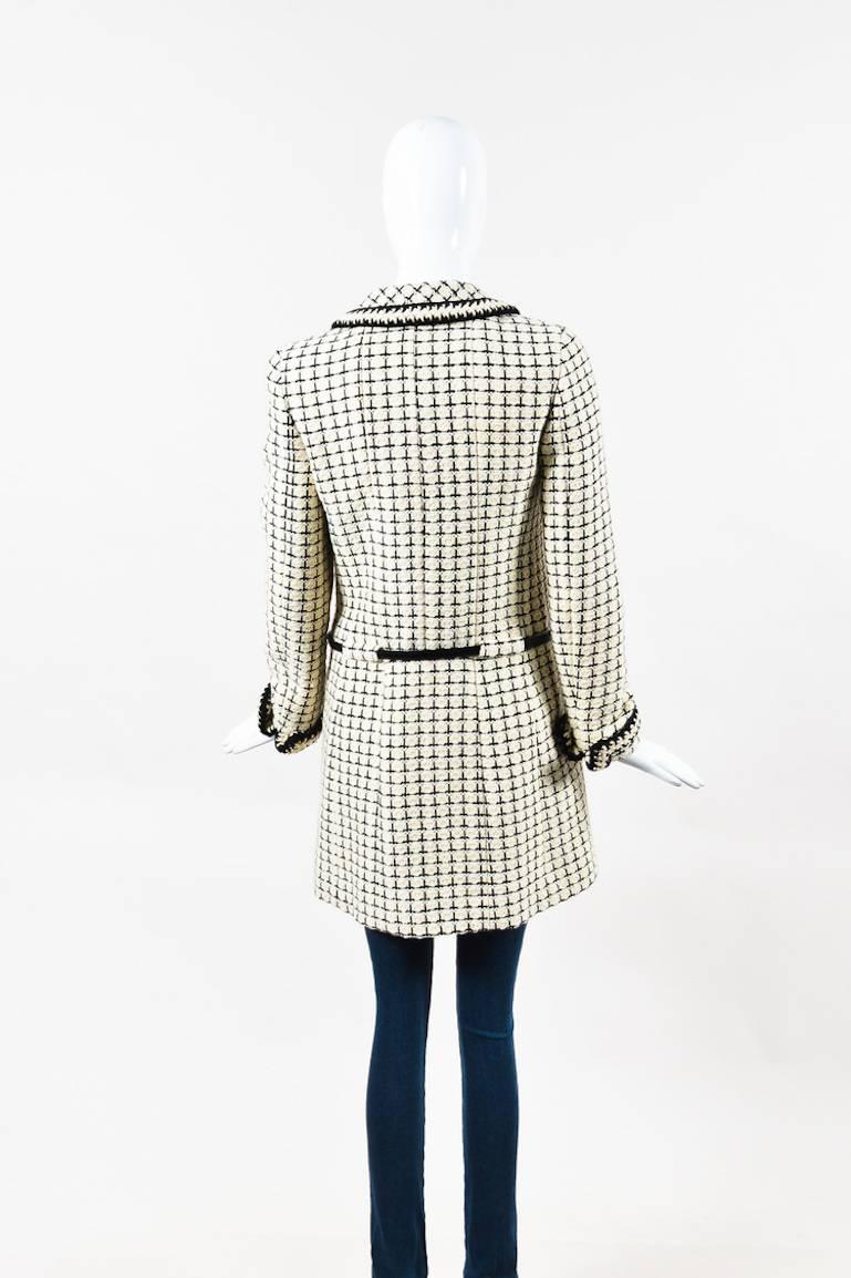 Black and cream tweed long coat by Chanel.  This coat features black trim throughout, grid pattern, and button front closure.  Two flat chest pockets.  Fully lined.  Leather belt at waist.

Additional measurements: Sleeve Length 23