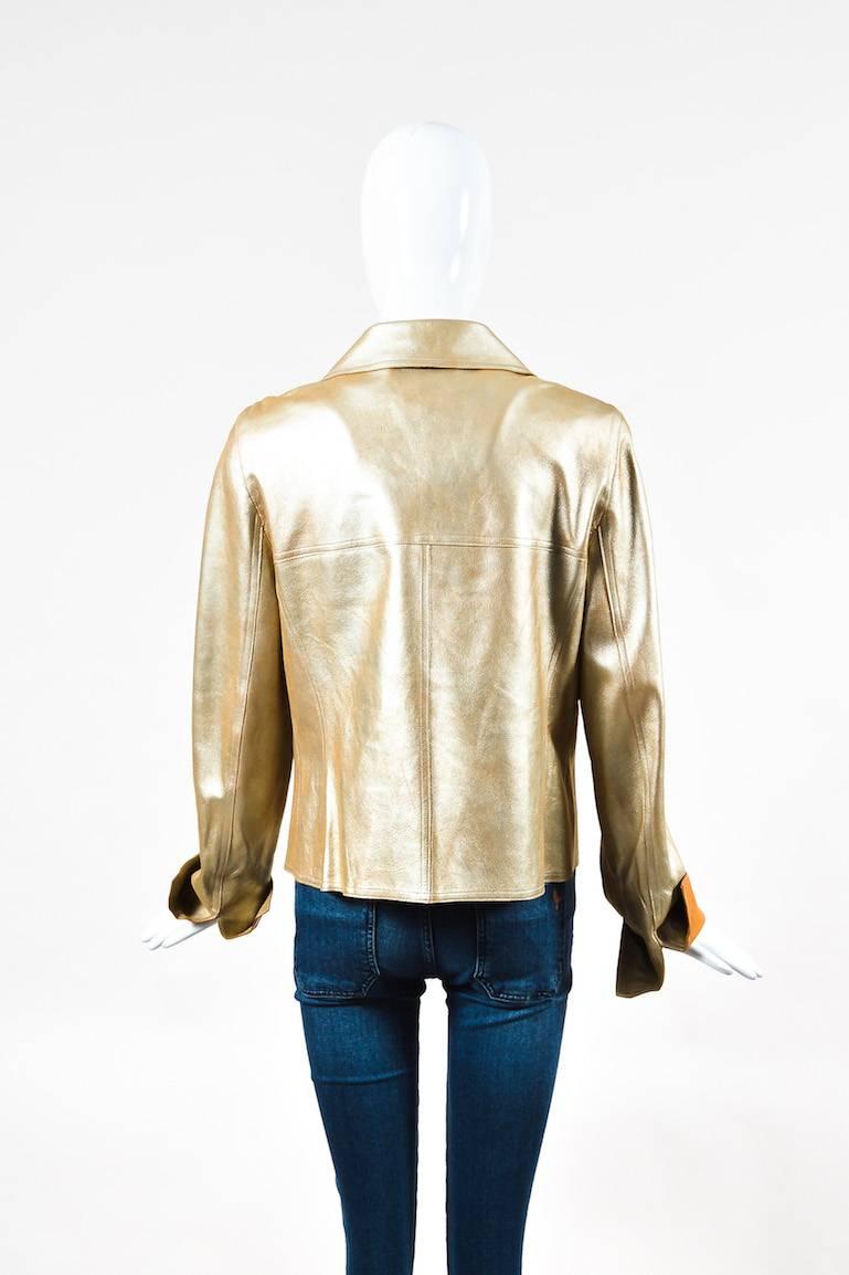 Metallic gold lambskin leather double breasted jacket from Chanel. Short collar. Decorative buttons have an embossed 'CC' logo. Two front open pockets. Slits on the ends of sleeves. Unlined. This jacket would pair well with black trousers and patent