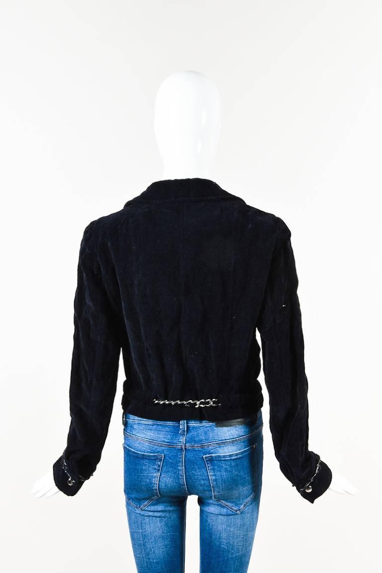 Navy velvet motorcycle jacket from Chanel features silver-tone hardware details. Collar and lapels. Front zipper for closure. Two front zip pockets. Cuffed sleeves with snap closures. Black satin trim down the front and along the ends of sleeves.