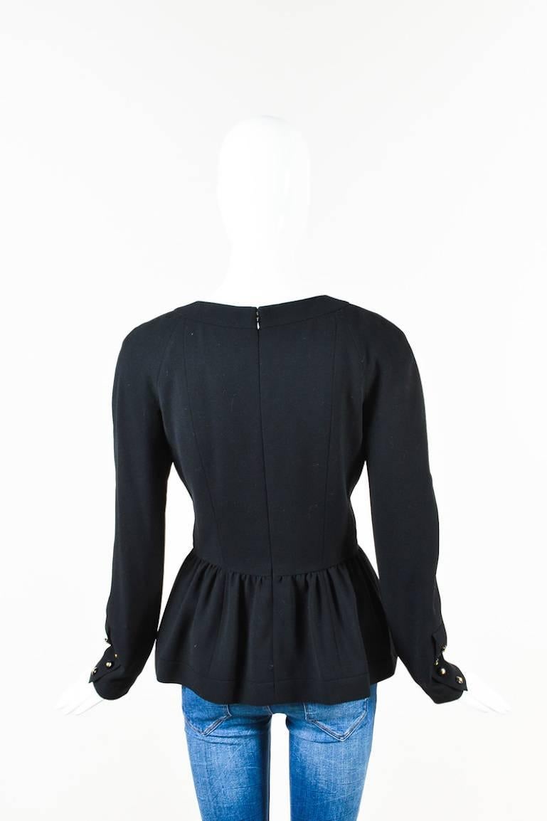 Features a round neck, buttoned pockets at the bust, and soft gathers radiating from a split peplum. Center back zip closure.