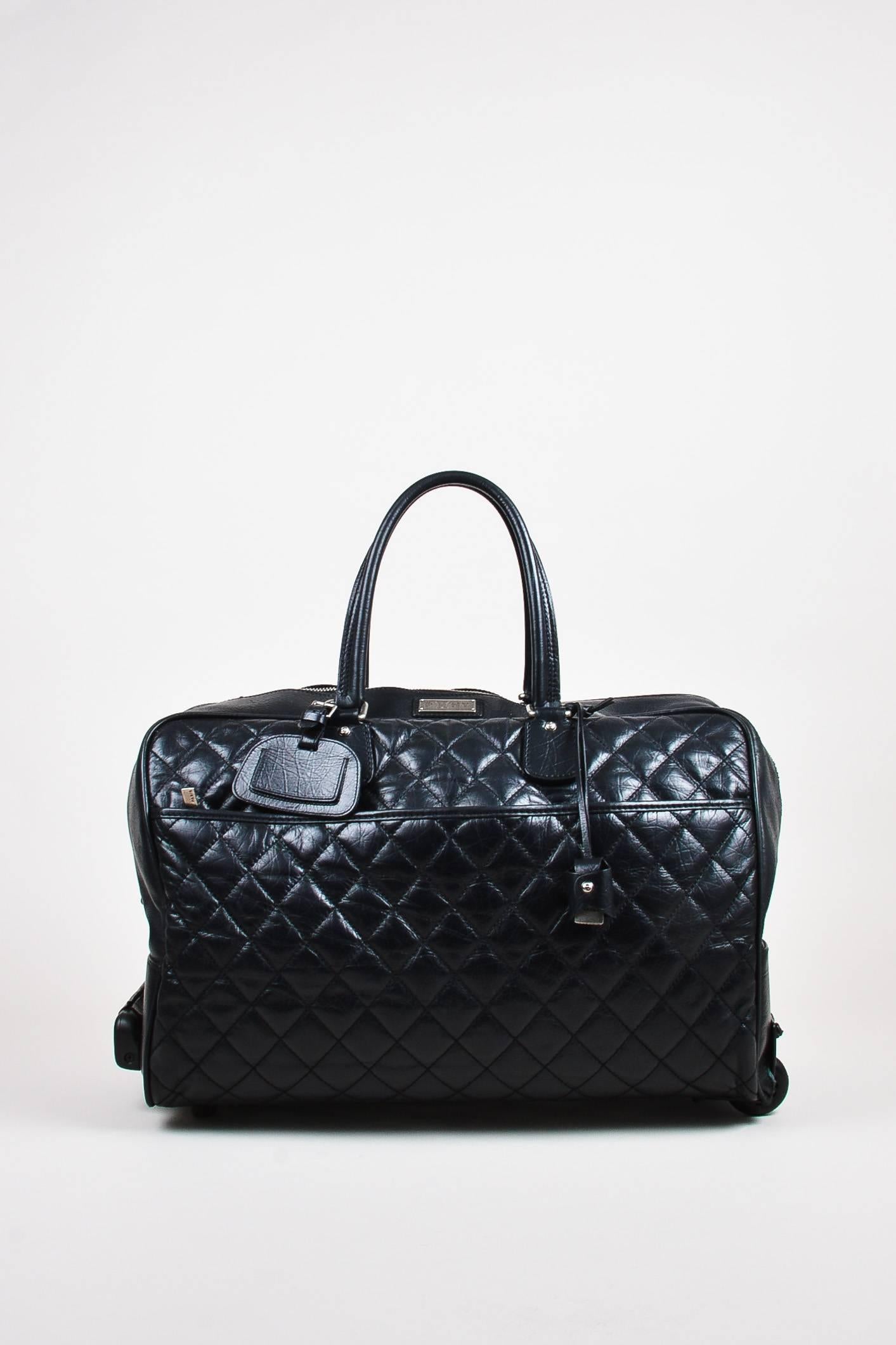 Stand out while traveling with this playful, yet chic luggage bag. Circa 2005-2006. Soft and supple, lightly padded lambskin leather. Diamond quilted stitching throughout. Silver-tone hardware. Attached retractable handle. Two roller wheels and two