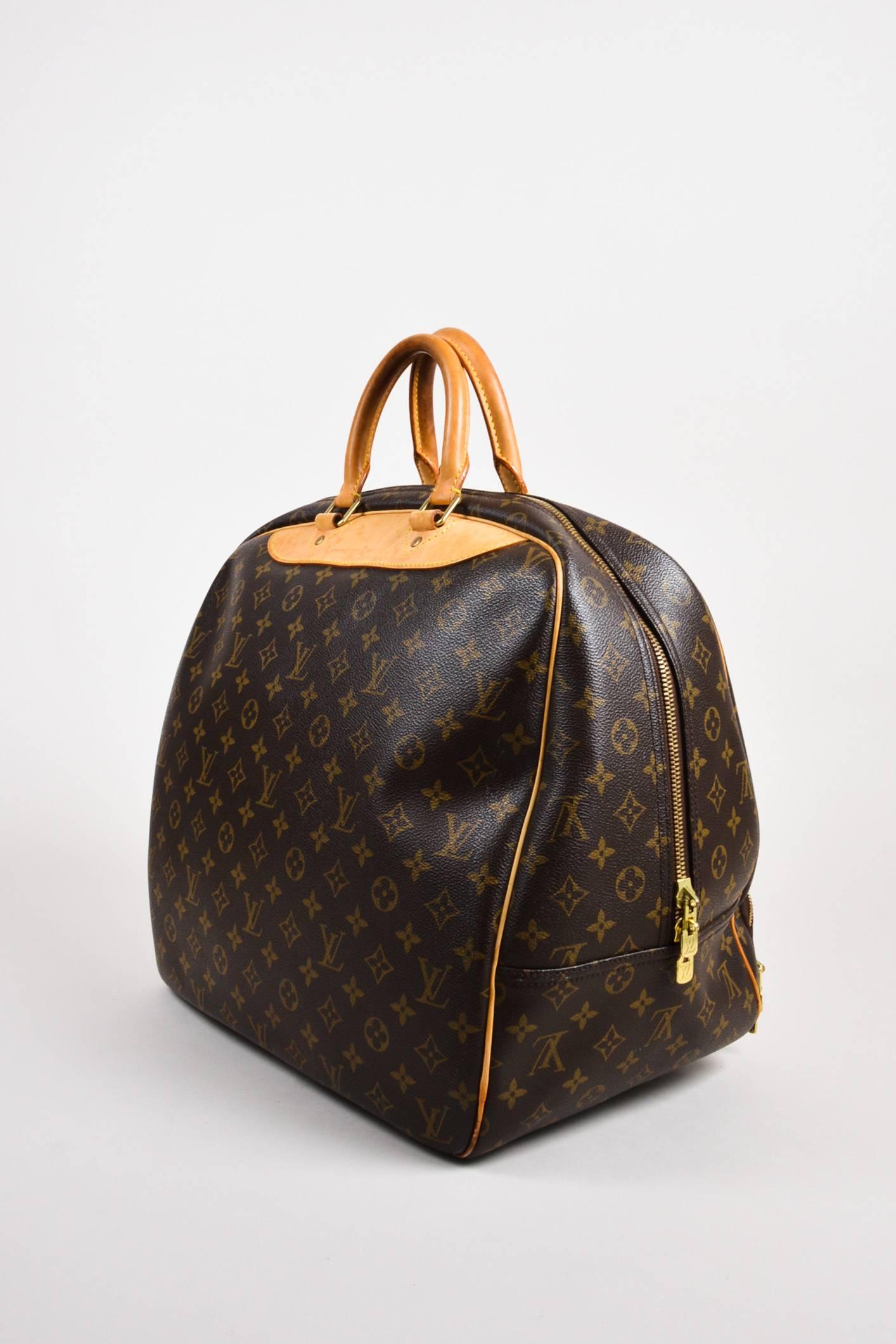 Brown and tan monogram coated canvas 'Evasion Travel MM' bag by Louis Vuitton.  This bag features gold tone hardware throughout, front zip pocket, and removable luggage tag.  Fully lined.  Zip top closure.  Date code: MB3097

Interior features: