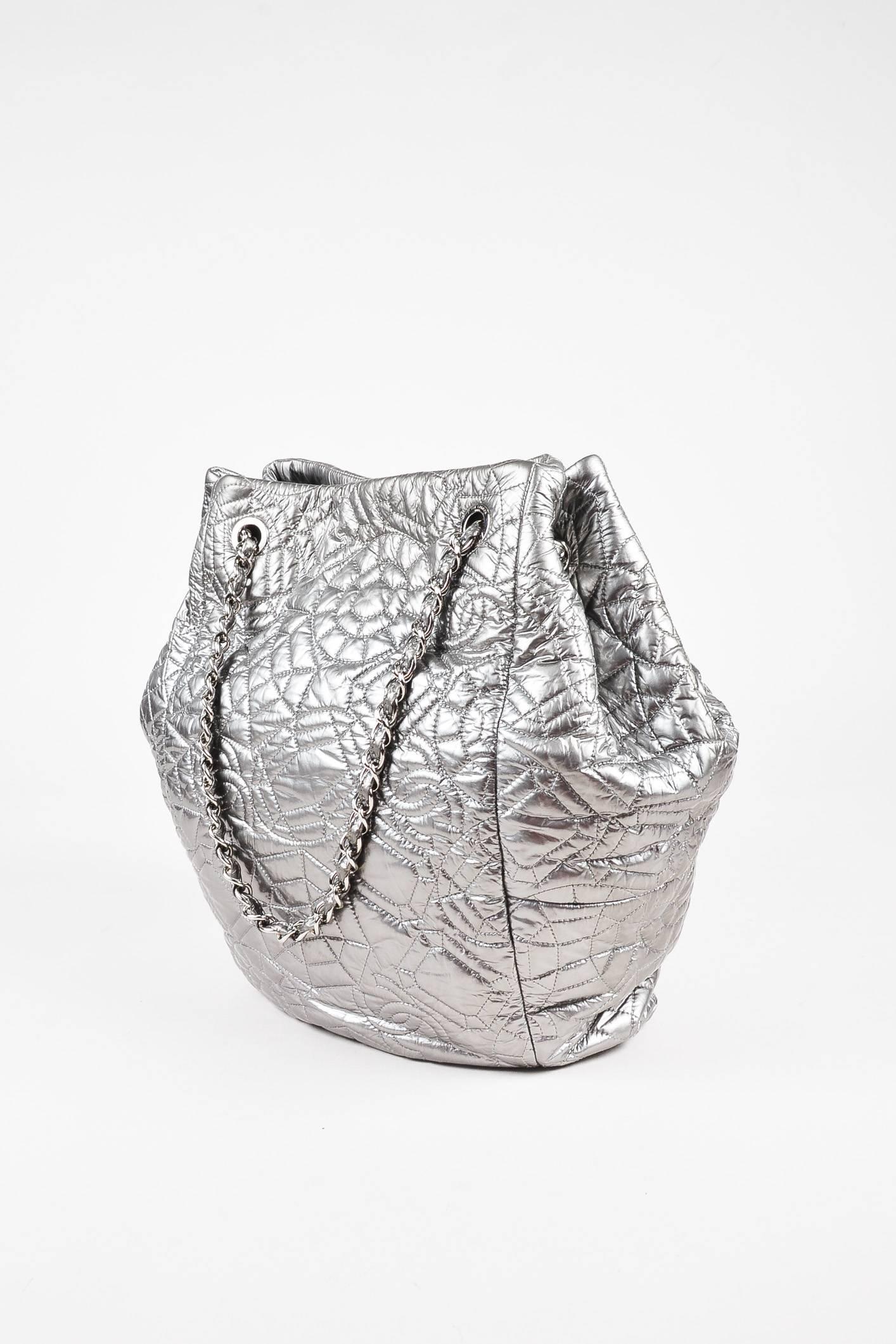 Silver metallic calfskin leather "Graphic Edge" tote handbag by Chanel. Features a geometric and "CC" pattern quilted throughout exterior. Silver-tone chain link and leather woven handles. Sides can cinch or expand. Silver-tone