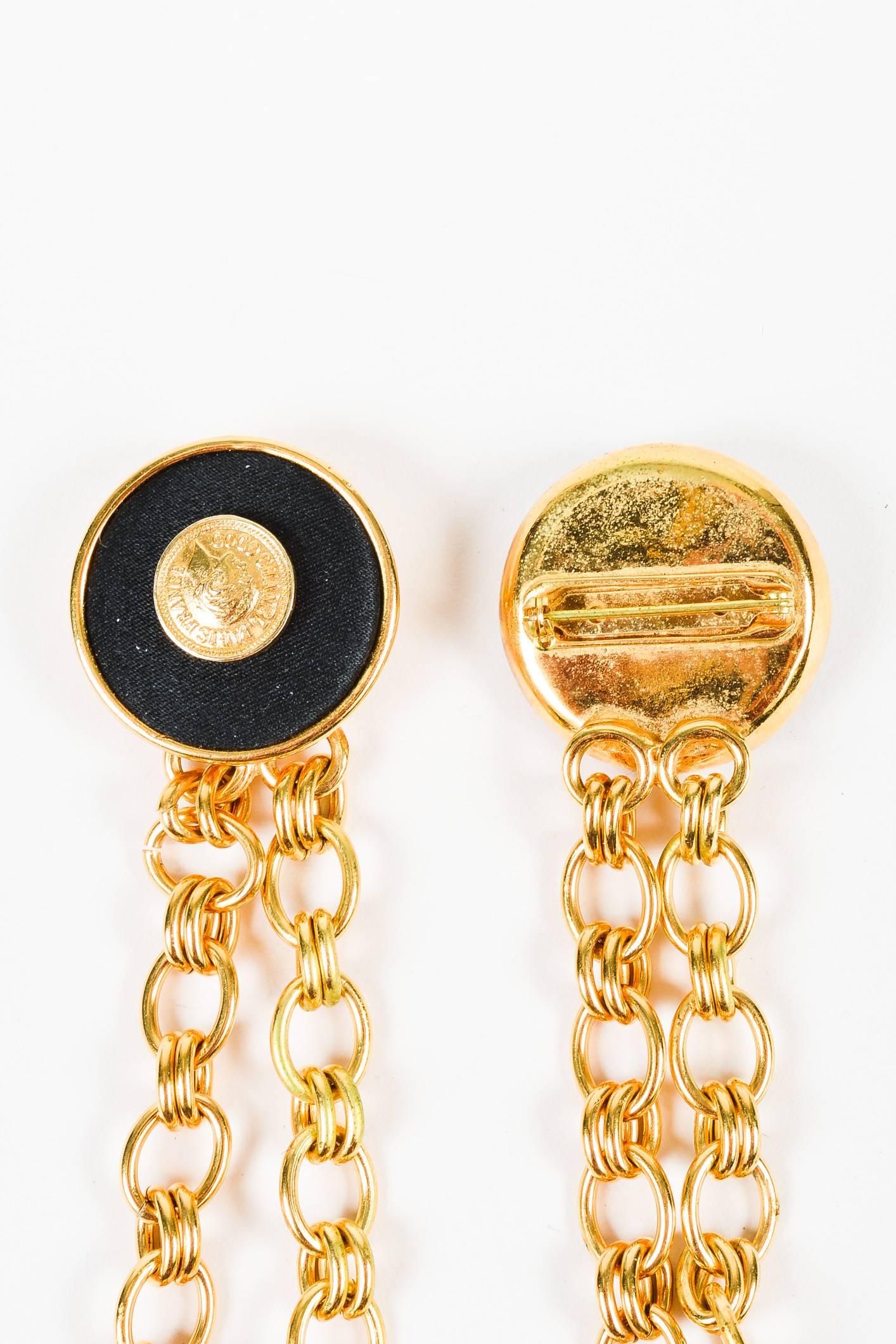 Vintage brooch with a unique flair. Gold-tone metal construction; polished finish. Satin covered medallions with 