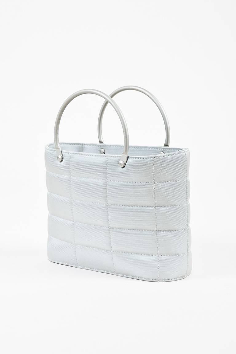 Made In: France
Fabric Content: Canvas

Item Specifics & Details: Light gray quilted canvas bag from Chanel circa 1997-1999. Structured base. Canvas has a slight metallic sheen. Two circular metal handles for wear. Interior lining features a zip