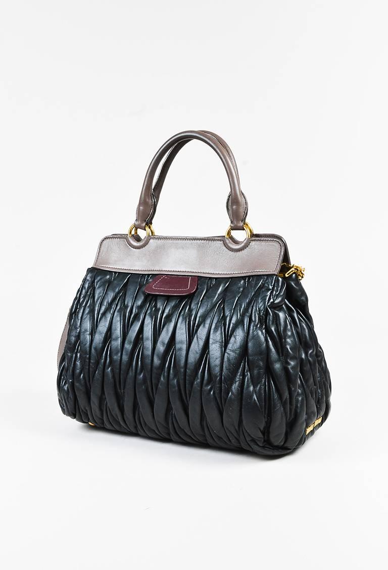 Color: Black,
Made In: Unknown
Fabric Content: Leather; Lining: Textile
Item Specifics & Details: Black matelasse leather and taupe trim satchel bag from Miu Miu circa 2012. Four gold toned bag feet. Two rolled handles for wear. One long adjustable