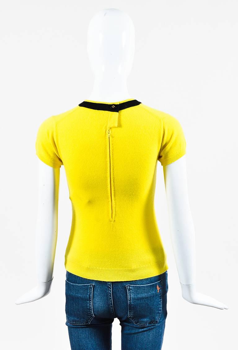Cashmere construction. Contrast black piping. Jewel neck. Short sleeves. Back button and zip closure. Unlined.

Size: Unknown
Made in: Unknown.
Color: Yellow
Content: Cashmere
Condition: Pre-owned. Light fuzziness throughout. Appears zipper has been