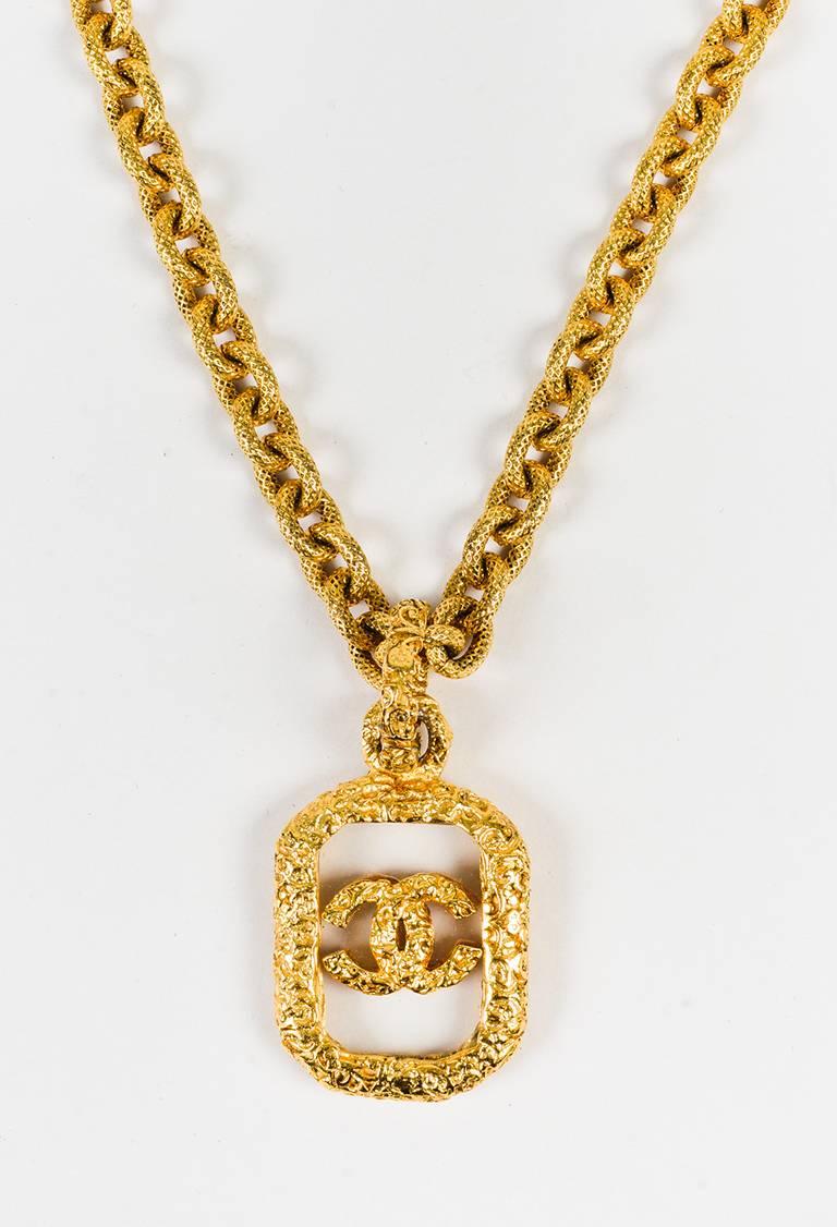 Gold-tone metal construction. Hammered finish. Rolo link chain. Carved dog tag pendant with 'CC' accent. Spring clasp closure.

Made in: France
Color: Gold
Content: Metal
Condition: Pre-owned. Slight oxidation throughout.

Total Length: 25.25