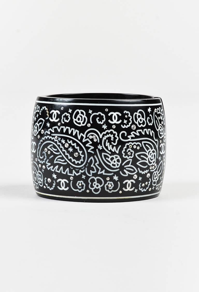 Resin cuff bracelet featuring 'CC' and floral engravings, a wide silhouette, crystal accents, and hinged opening. Released circa spring 2009.

Color: Black,White,
Made in: France
Fabric Content: Resin, Crystals, Metal
Condition: Pre-owned. Residue