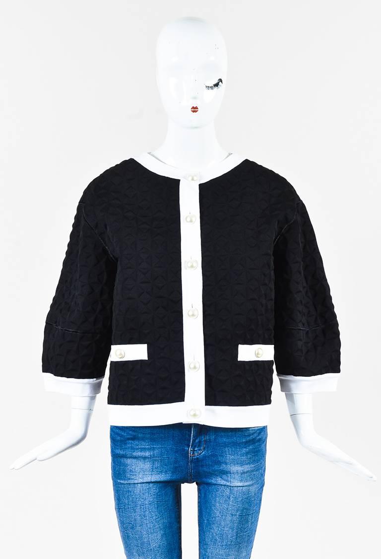 Black and white textured long sleeve jacket from Chanel. Faux pearl buttons down the front for closure. Rounded neckline. Two faux open pockets on the front with button details. Embroidered trim. Original retail of $4,245.

Size: 44 (FR)
Color:
