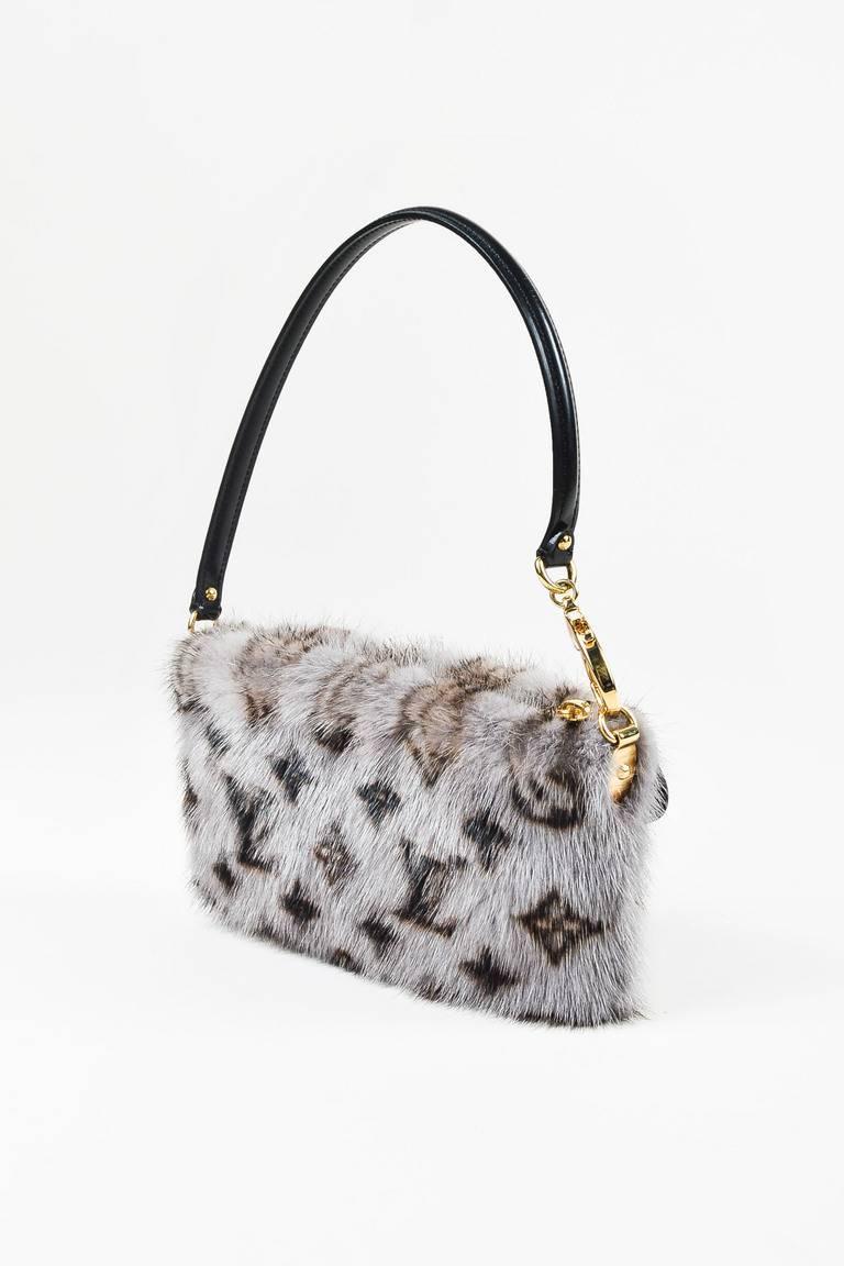 A luxurious take on the typical wristlet. Circa 2009. Super soft mink fur exterior. Signature monogram print. Gold toned hardware. Leather trimmings. Ribbed top strap with lobster claw clasp closure; can be worn around wrist or over the shoulder.