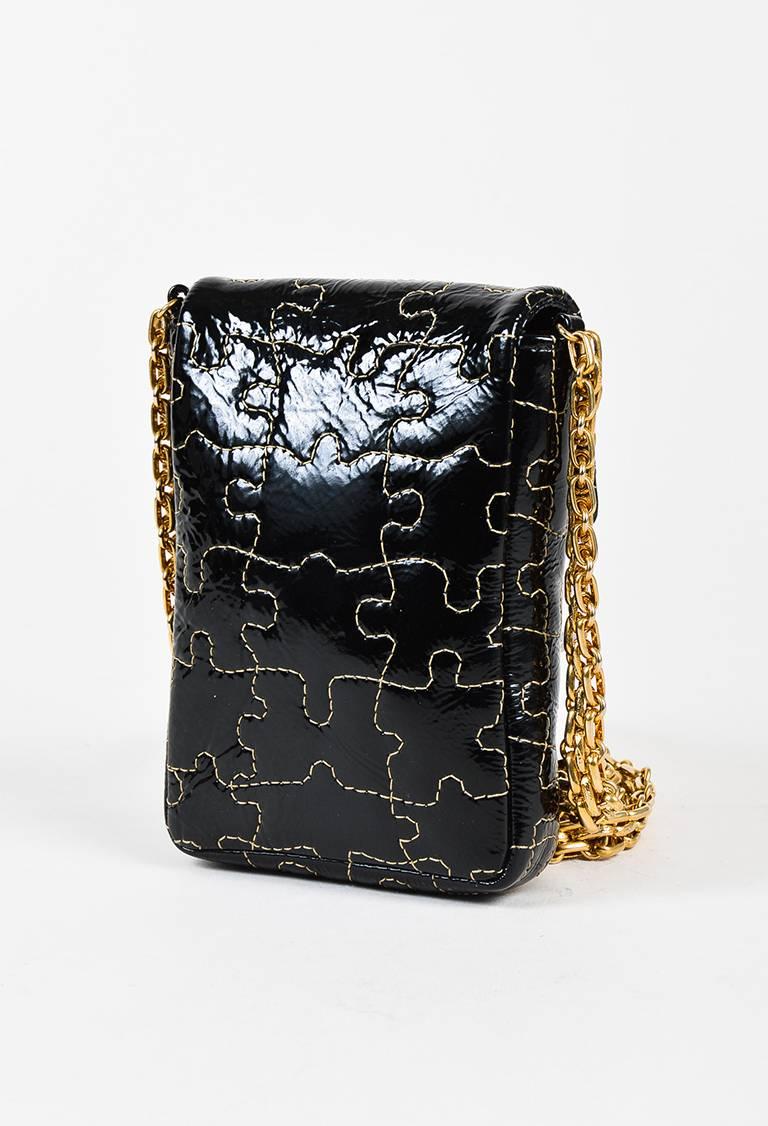 Black patent leather puzzle piece quilted crossbody bag from Chanel. Front flap with a gold-tone turn lock closure. Gold-tone chain link strap for wear. Leather interior.

Color: Black,
Made in: Italy
Fabric Content: Patent Leather; Lining: